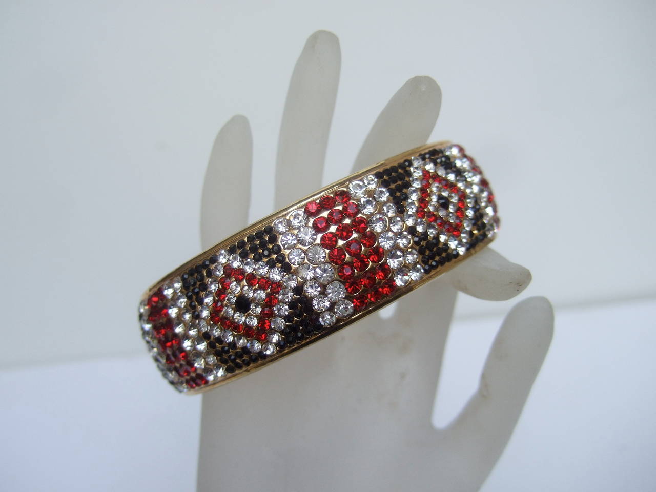 Bob Mackie Bracelet bangle incrusté de cristaux. Cet élégant bracelet d'inspiration art déco est orné de rubis brillants, de cristaux de jais et de diamants
Les cristaux scintillants sont conçus dans des motifs géométriques sévères

La bande