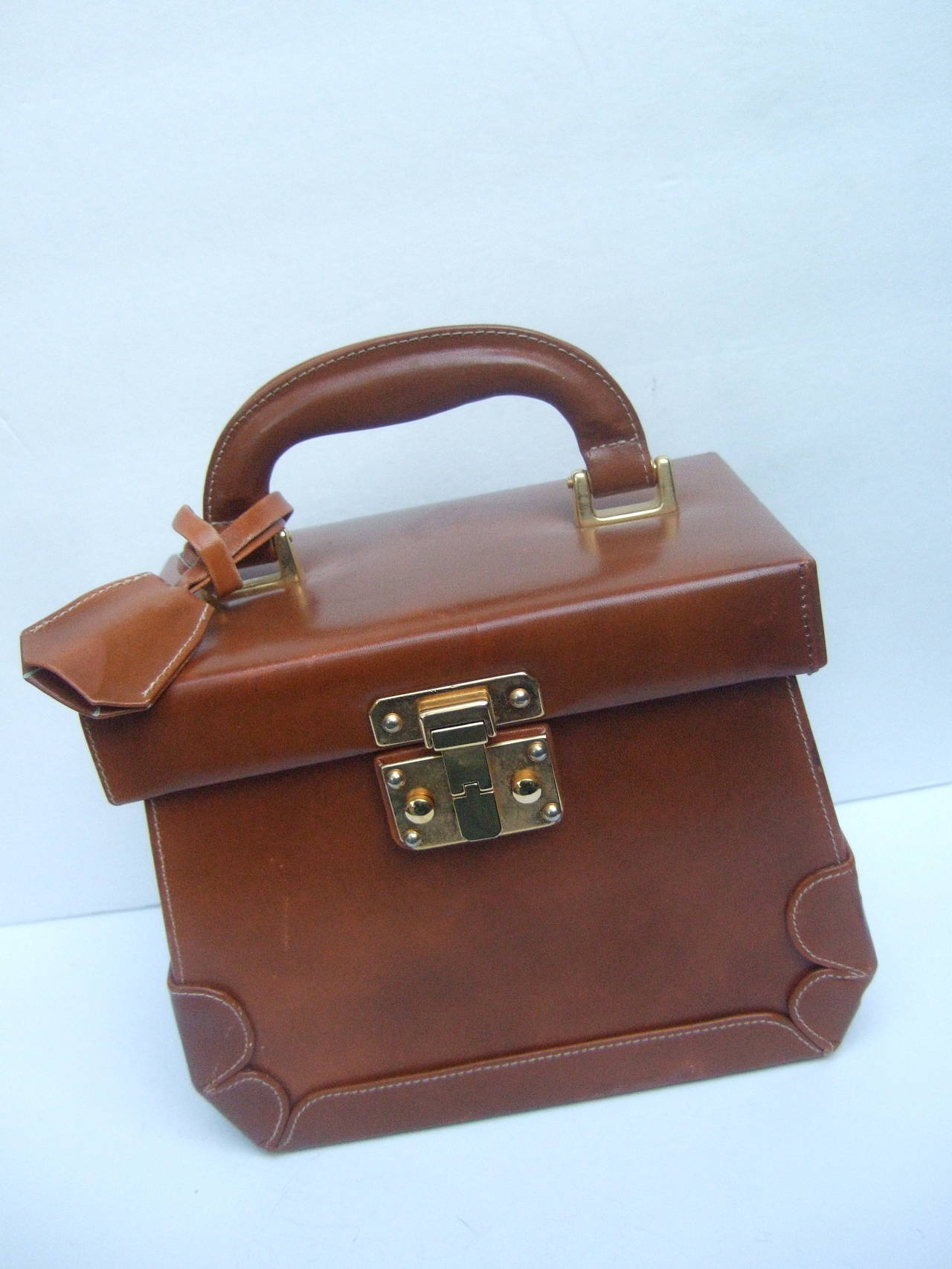 Henri Bendel Caramel brown leather train case handbag Made in Italy
The posh handbag is covered in brown leather with sleek gilt metal hardware
The stylish box style handbag is designed with a gilt metal clasp mechanism 
The lock key for the