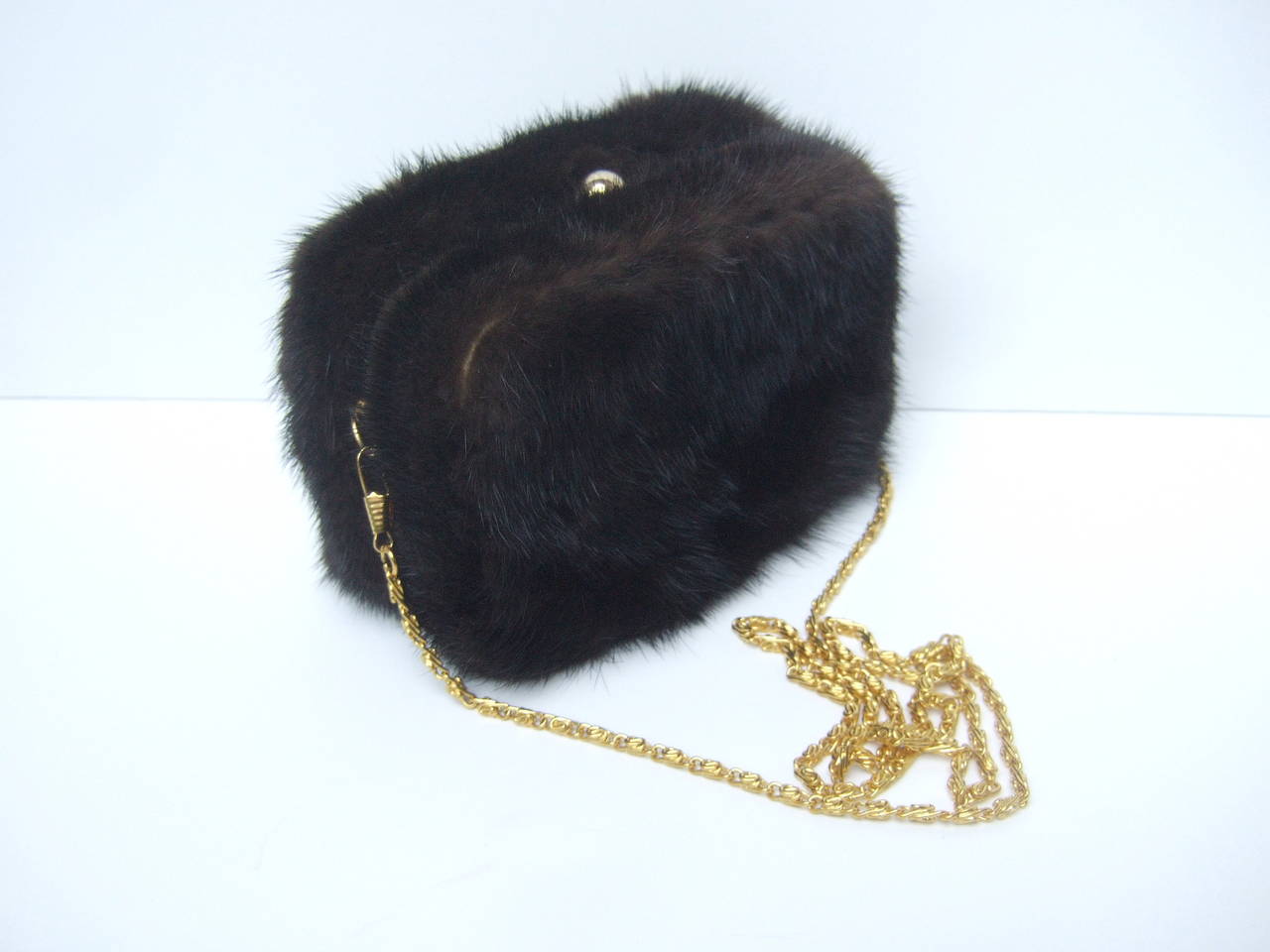 Luxurious mink fur diminutive evening bag c 1980s
The elegant mink cubed shaped evening bag is covered with plush mahogany dark brown fur in all sides. The clasp & chain strap are designed with sleek gilt metal

The versatile design converts from