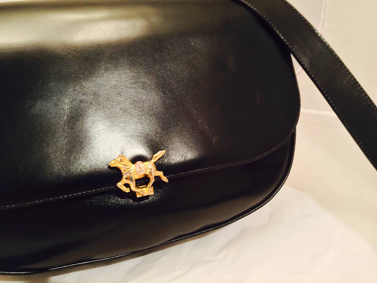 Wonderful crossbody black leather saddle bag adorned with gilt enamel horses displaying the camerino logo.