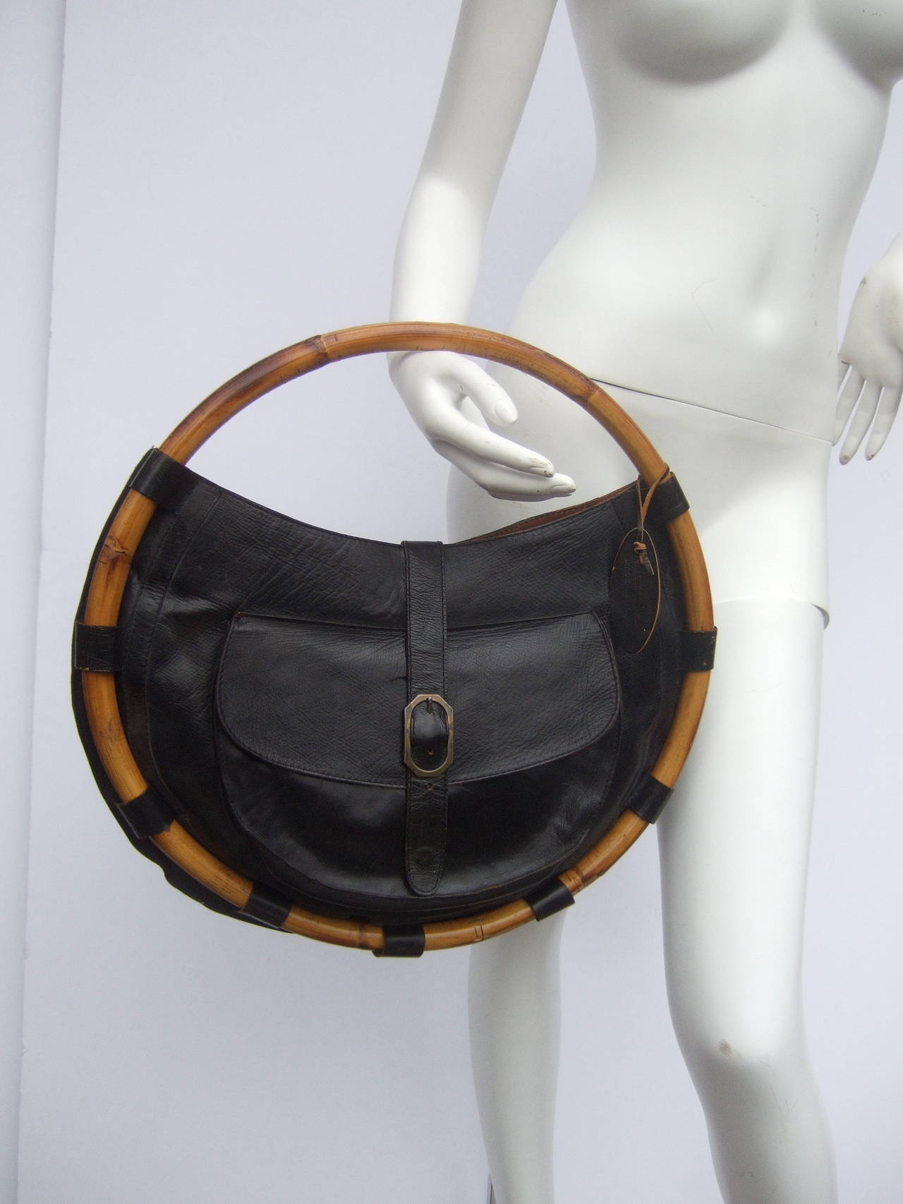 Avant-garde black leather circular bamboo handbag Made in Italy
The unique Italian large scale handbag is covered with black leather on the front & back exterior sides. The stylish retro handbag is framed with a bamboo wood ring that circles