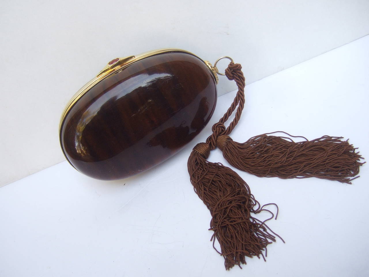 Saks Fifth Avenue Tortoise shell lucite evening bag c 1970s
The elegant oval shaped clutch bag is covered with brown lucite panels
Designed with a sleek gilt metal clasp frame that circles the evening bag

The clasp is adorned with a carnelian
