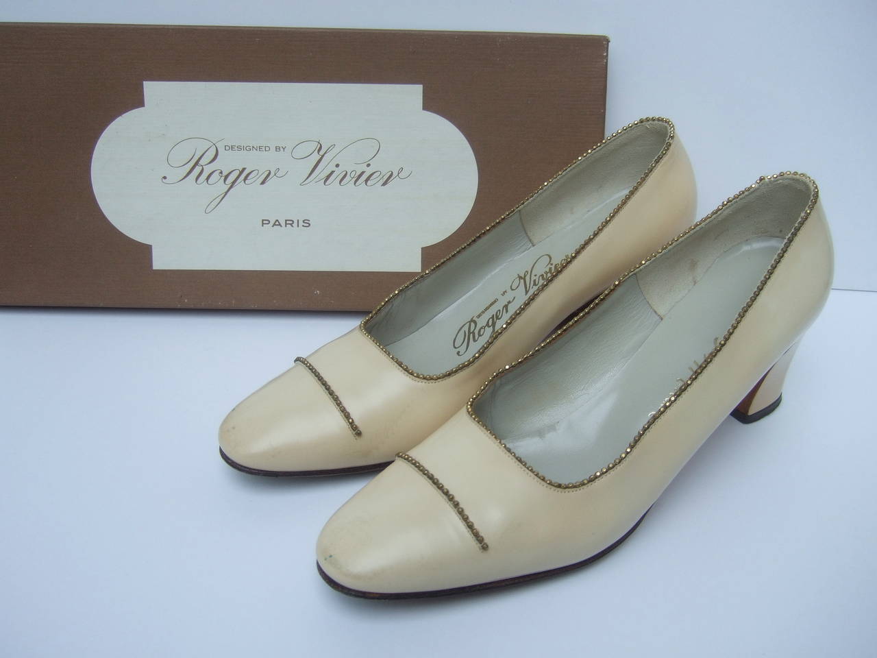 Roger Vivier Paris Ivory leather beaded pumps for Saks Fifth Avenue c 1970
The elegant retro pumps are embellished with restrained gold hematite glass beaded trim. The classic designer pumps are covered with ivory color leather
The stylish retro