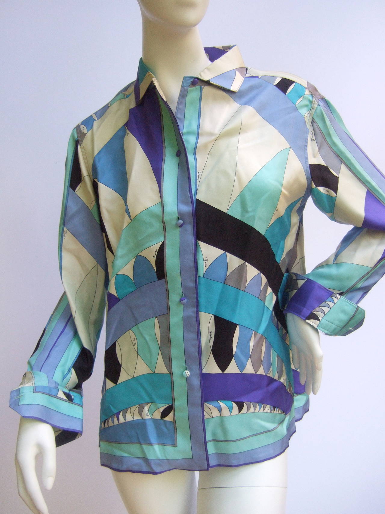 Emilio Pucci Iconic graphic print silk blouse for Saks Fifth Avenue c 1970
The vibrant op art silk print is a collage of blue hues of aqua, turquoise, azure, violet, gray & black. The bold colors illuminate against the white silk
