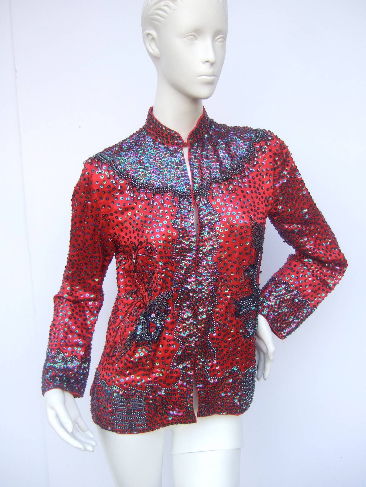 Exotic silk beaded & sequined crimson evening jacket c 1980
The exquisite hand beaded silk jacket is designed with elaborate 
sequined & beaded embellishments 

The yolk, borders & cuffs are encrusted with iridescent sequins
combined with