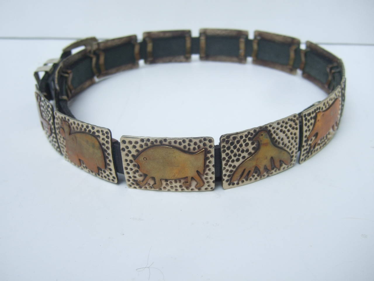 Hand forged mixed metal artisan animal belt designed by Lunacy c 1970s
The unique artisan black belt is designed with silver & brass metal tiles
Each tile depicts a different type of animal figure. The animals & reptiles
range from