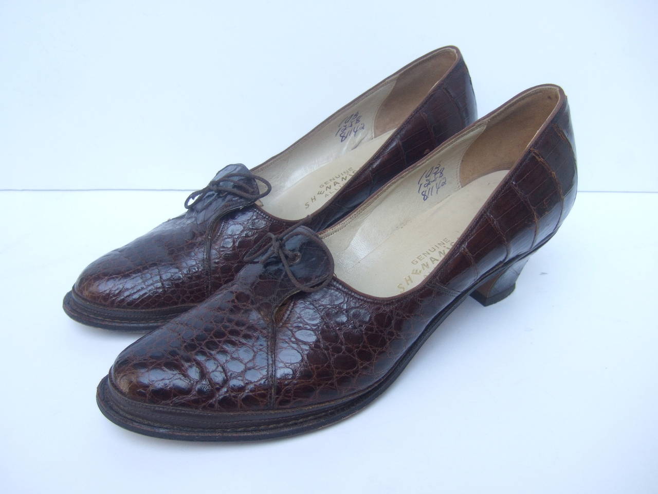 Genuine alligator retro brown pumps c 1950s
The stylish retro shoes are designed with mahogany brown alligator skin 
The reptile pumps are accented with a subtle bow string detail 

The interior is lined in ivory leather & suede labeled
Genuine