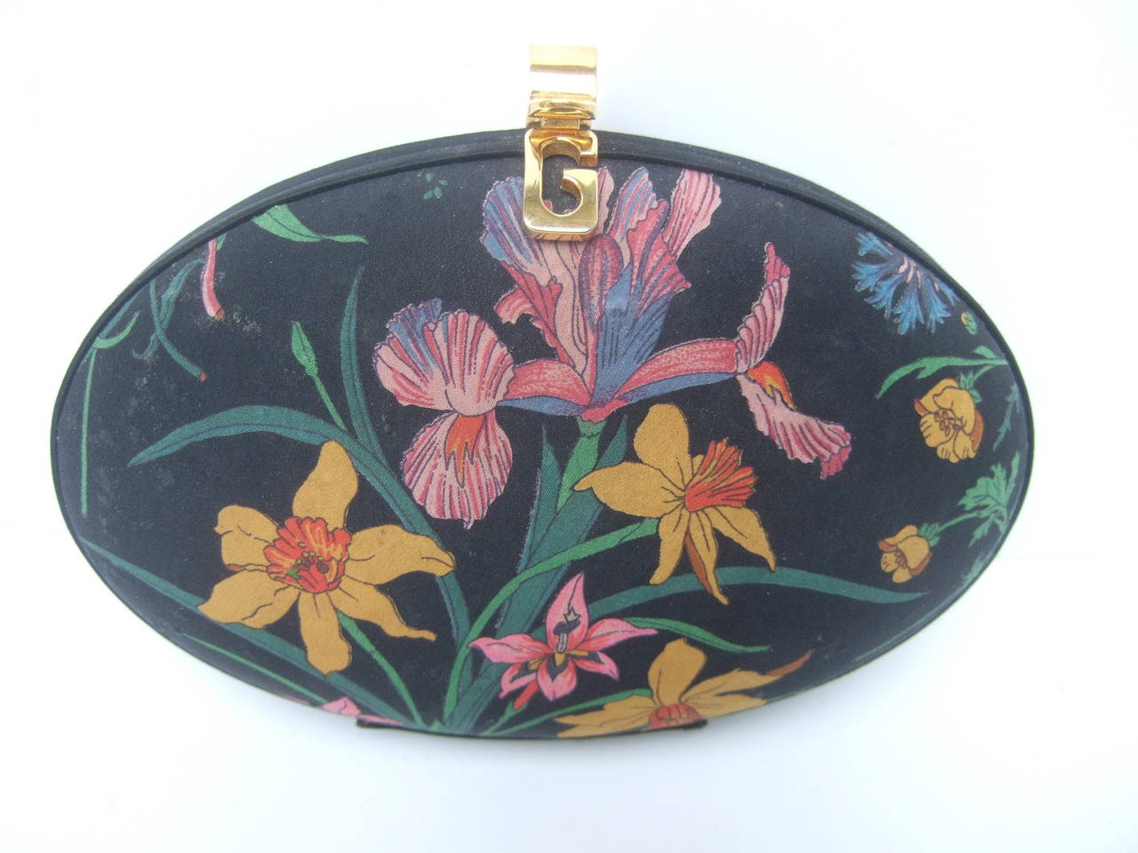 Gucci flower print egg shaped clutch bag c 1980s
The rare Gucci handbag is designed with a cloth floral print covering
Both exterior sides have a field of spring time flowers set against the
black cloth background. A black satin band circles the