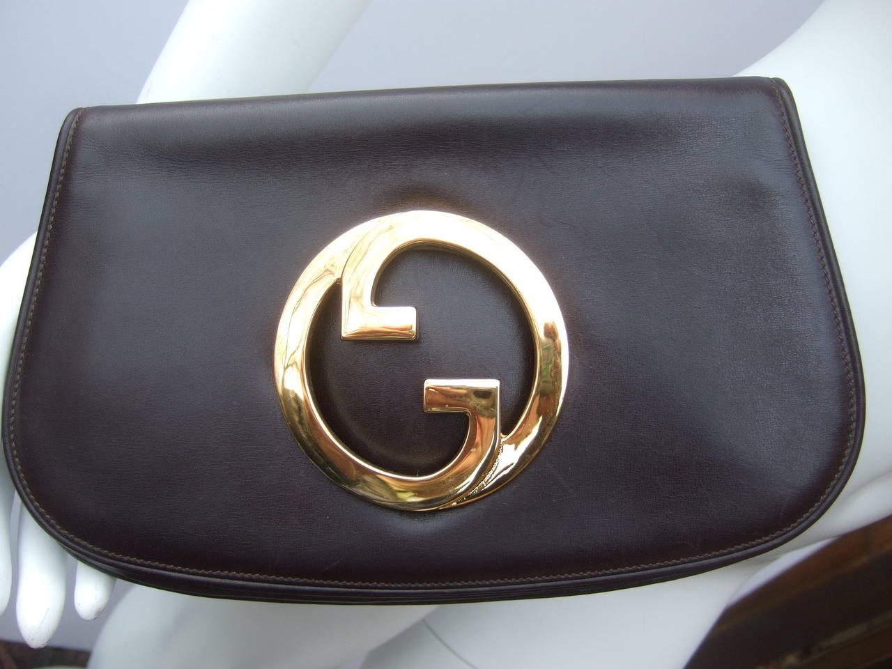 Gucci Iconic chocolate brown leather blondie clutch c 1970
The chic retro clutch bag is covered with dark brown
leather adorned with Gucci's massive gilt metal initials

The border edges are designed with subtle restrained stitching
The