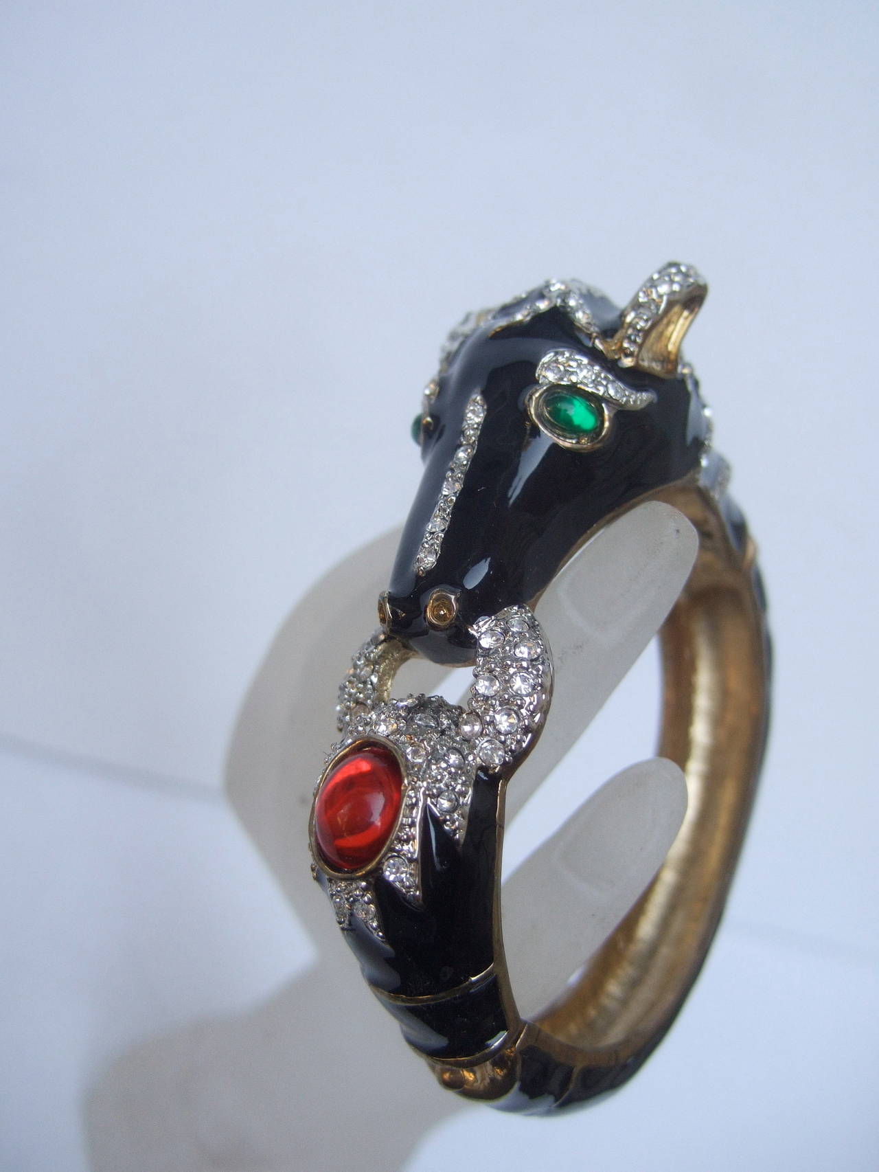 Jet enamel jeweled equine bracelet c 1980
The elegant horse theme bracelet is covered with black enamel
Embellished with emerald green color cabochon eyes 
The horses features are accentuated with glittering diamante 
crystals & a large ruby