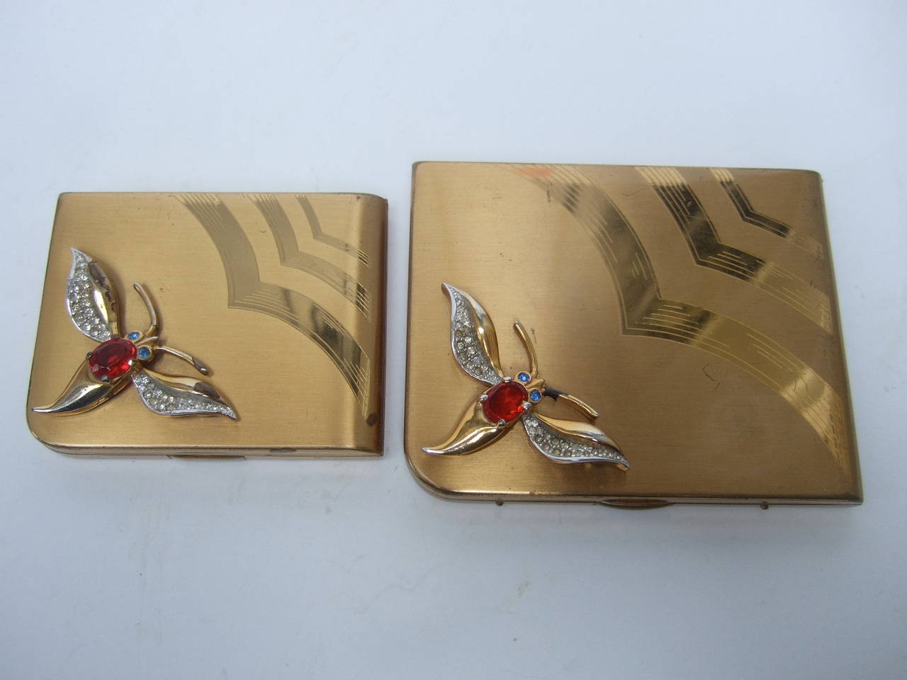 Art Deco Jeweled cigarette case & vanity compact set c 1950
The opulent retro cigarette case & vanity compact are embellished
with crystal butterflies. The fluttering butterflies are encrusted with
a large ruby color crystal accented with