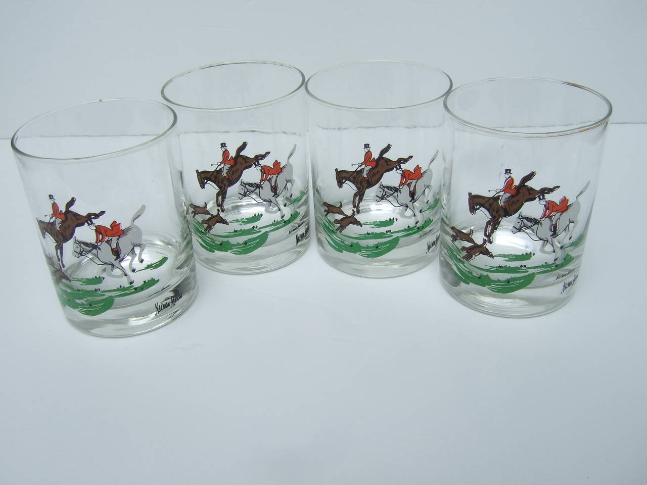 Neiman Marcus Set of four equestrian drinking glasses c 1980
The four bar glasses are designed with decal scenes of English 
style horsemen with hunt dogs in pursuit of an elusive fox 

Each glass has the same hunt scene illustration
Each glass