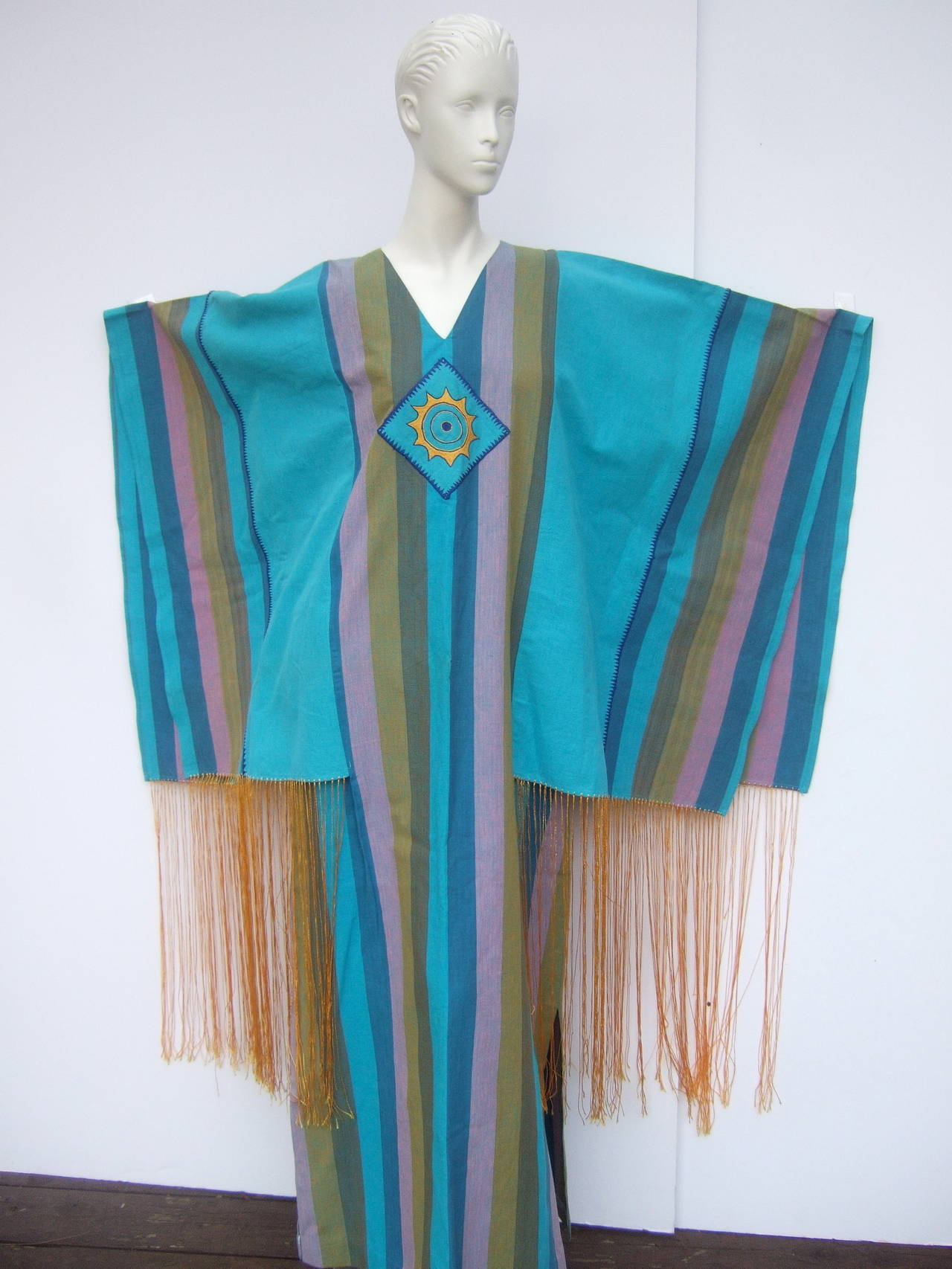 1970s Spectacular angel wing caftan designed by Joesfa
The exotic cotton caftan is a myriad of soft muted colors;
Aqua blue, lavender, mauve, olive green, brown vertical stripes

The center of the caftan is designed with an applique