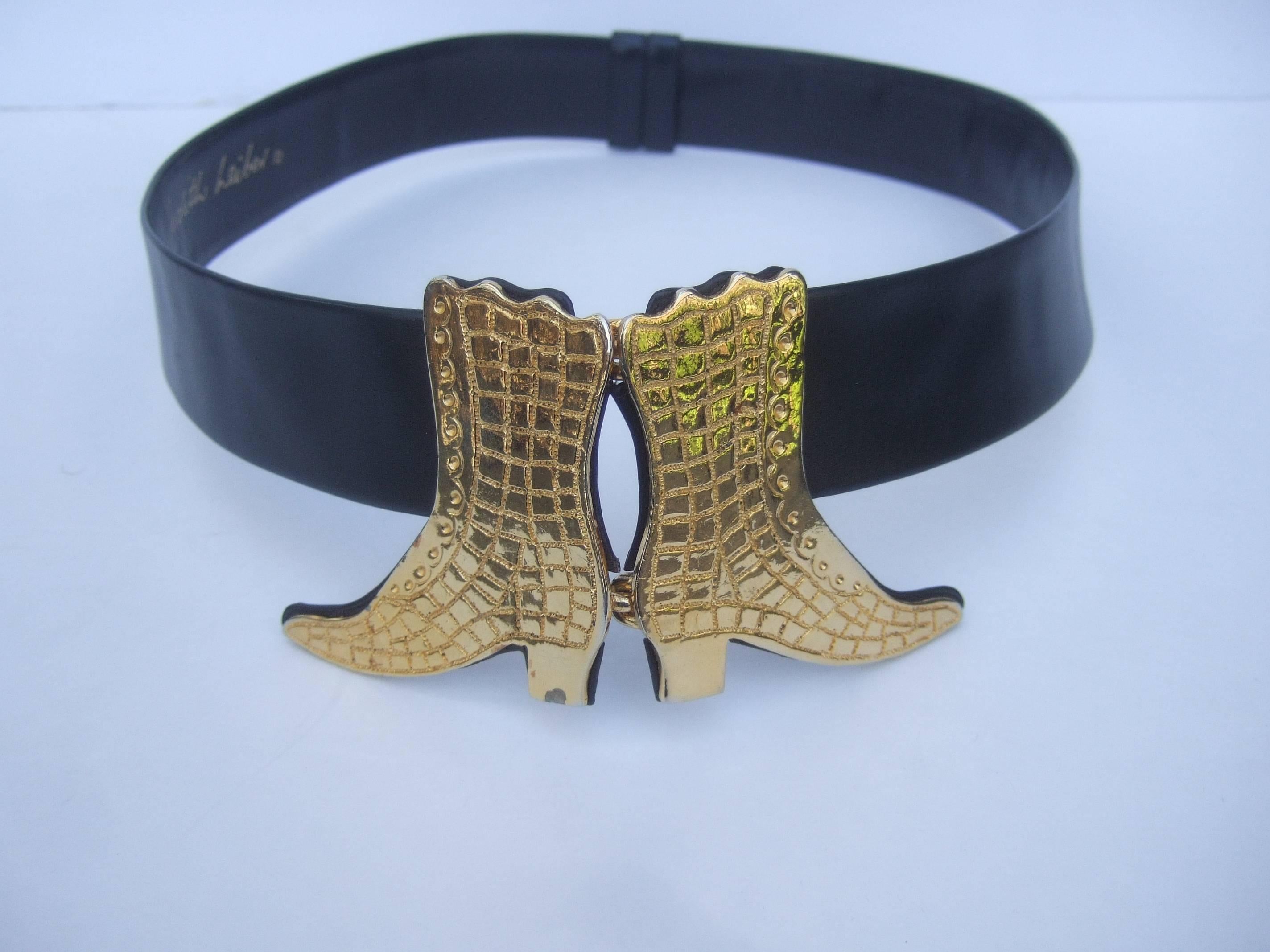 Judith Leiber Gilt boot buckle black leather belt circa 1980s
The stylish belt is adorned with a pair of large scale 
gilt metal boots that serve as the hinged buckle 

The black leather belt is adjustable and crosses
over numerous waist sizes