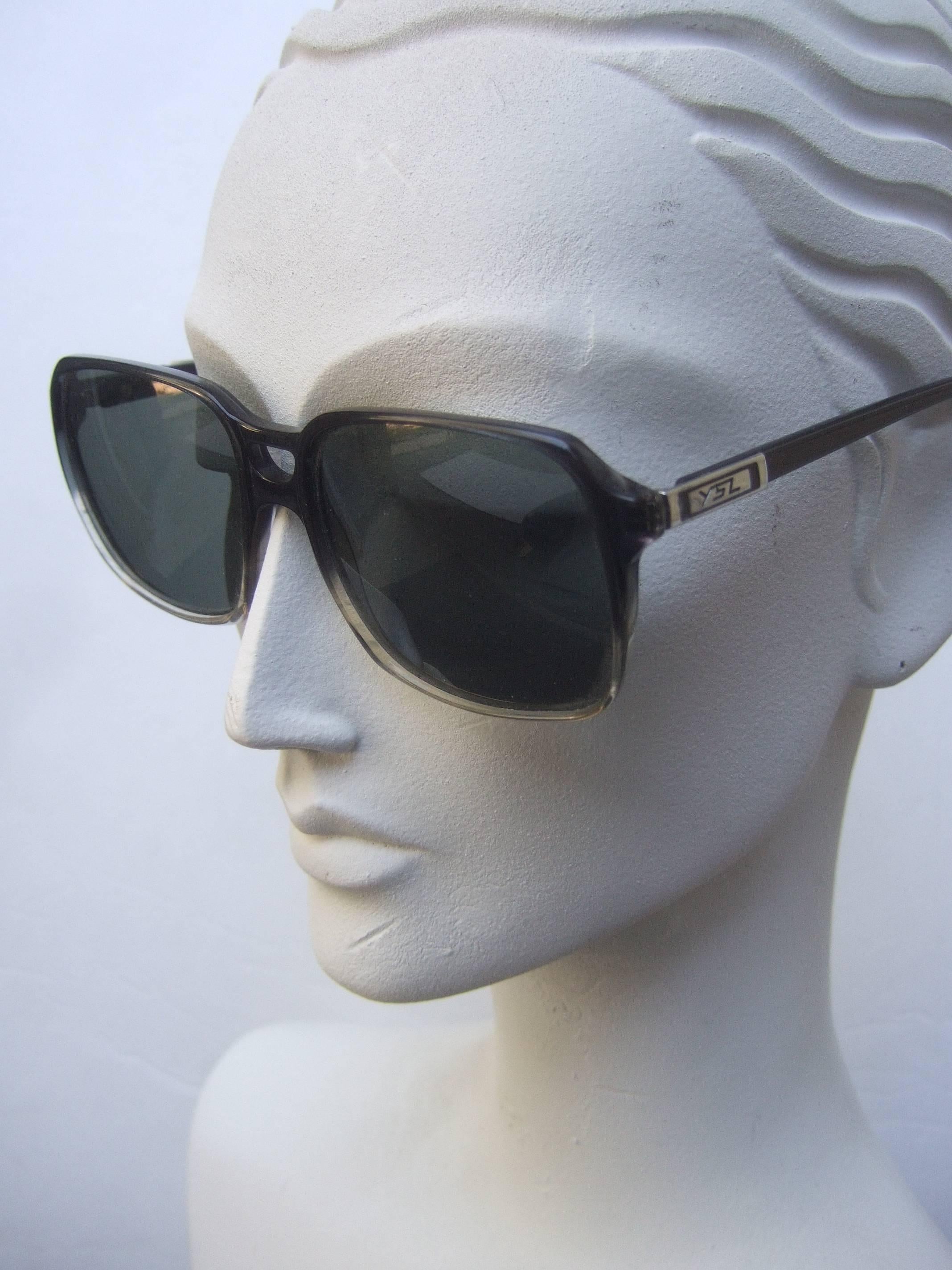 Yves Saint Laurent Gray lucite women's sunglasses c 1980s
The sleek gray lucite frames are paired with smoke
gray plastic lenses

The sides are adorned with chrome metal plates
inscribed with YSL initials on both sides

The interior arm of