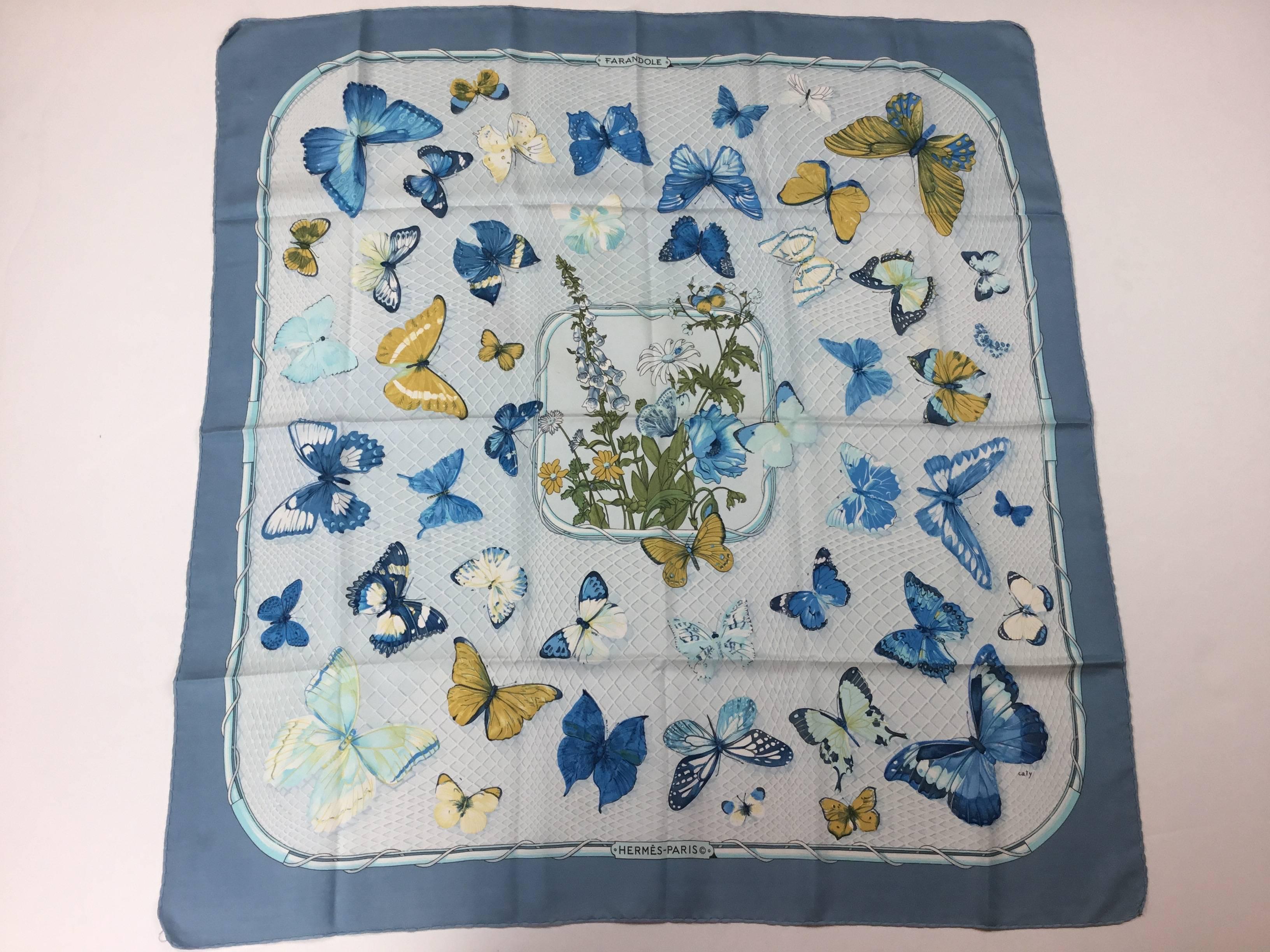 This Hermes is so very subtle and pretty. Butterflies hover around a central portrait of foxgloves, poppies, and daisies. Various species are depicted. 
Lovely muted blues and beige. Designed by Cathy Latham. 1985. 
Great condition aside from one