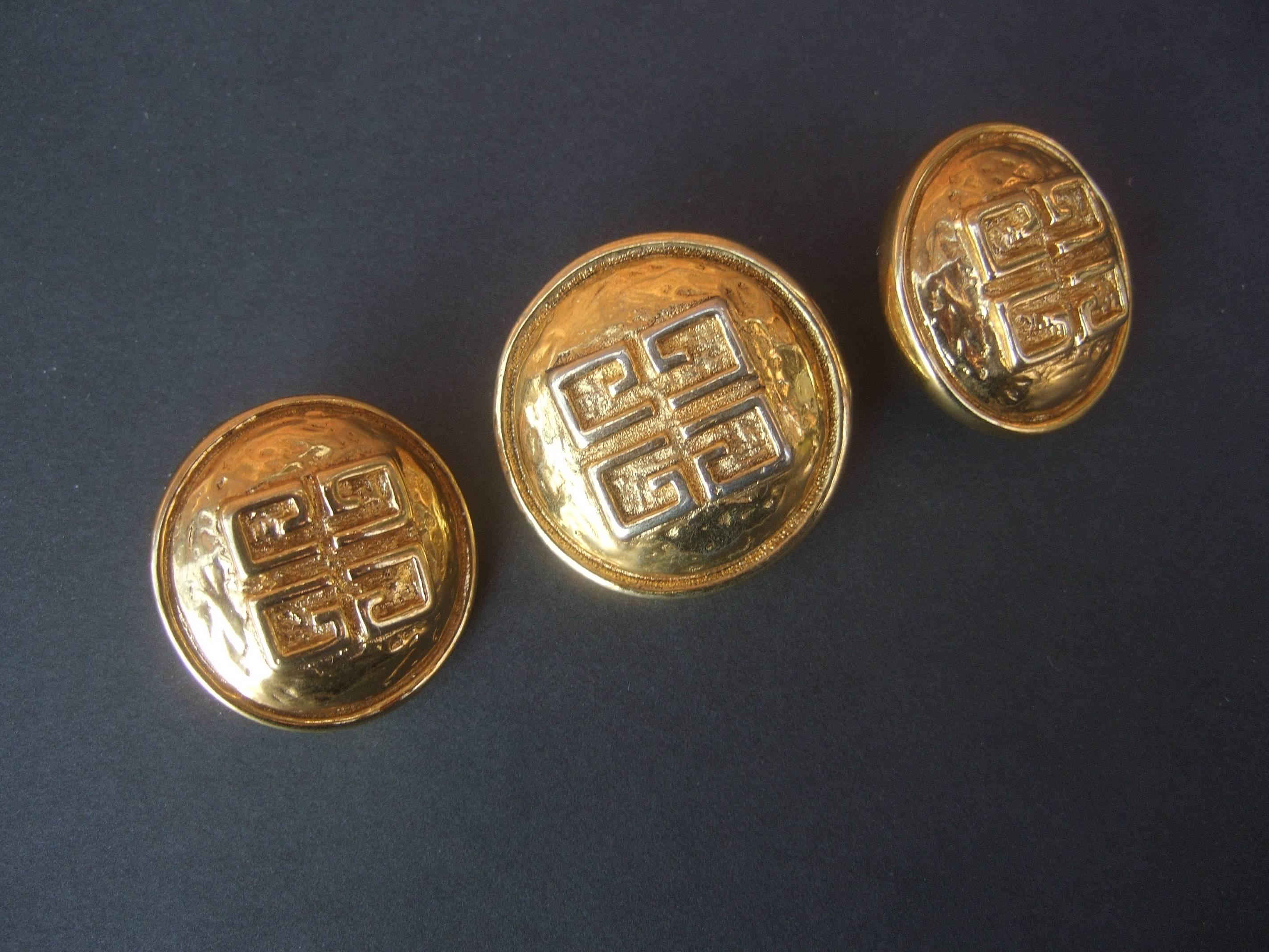 Givenchy France Gilt metal brooch & earrings ca 1980s
The elegant brooch & earrings are adorned with 
Givenchy's signature gilt metal G.G. initials 

The circular base has a hammered textured finish 
in contrast to Givenchy's smooth shiny gold
metal