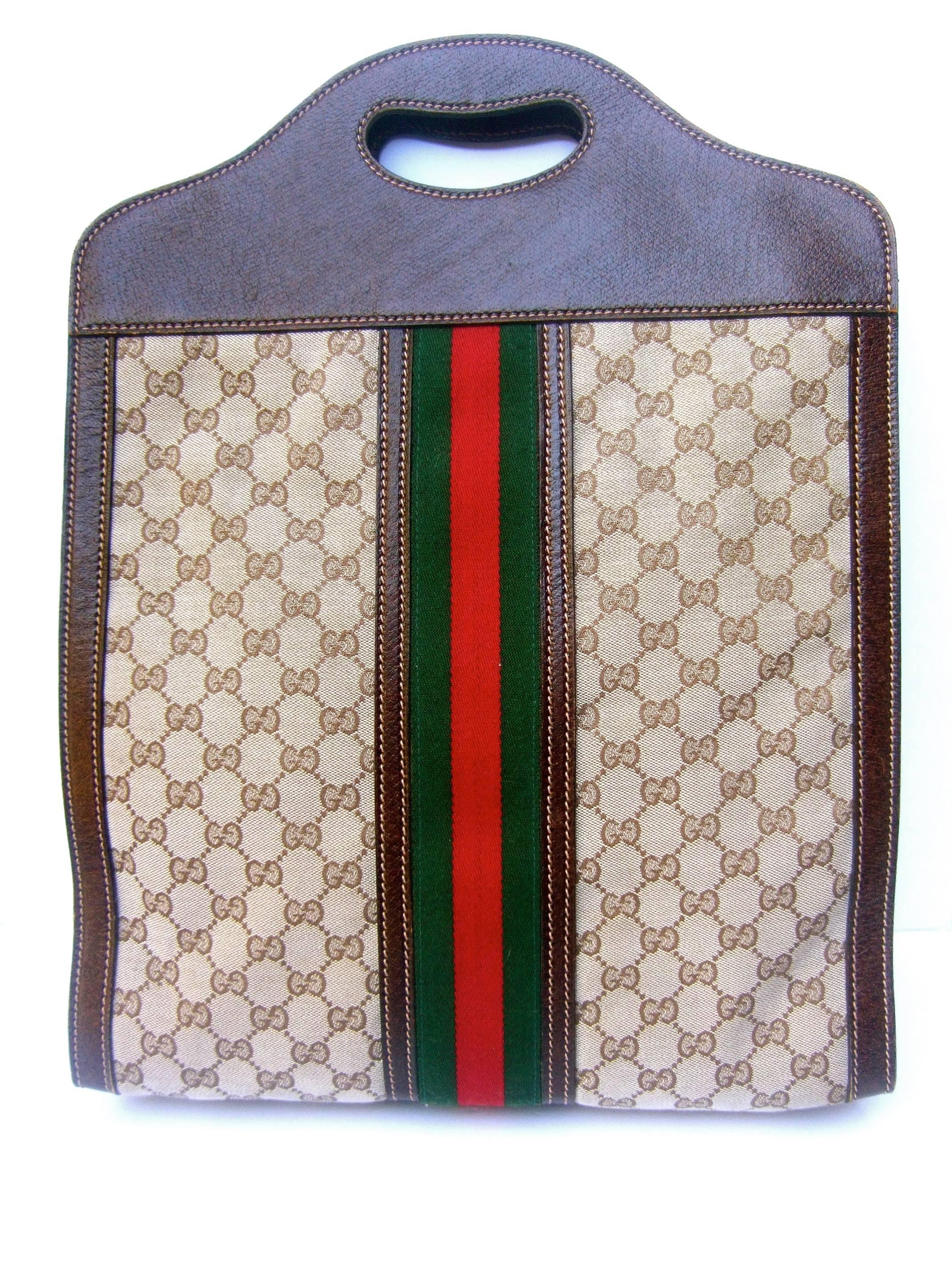 Gucci Italy Brown Leather and canvas large tote bag ca 1970s
The stylish Italian tote bag is framed with brown leather 
with saddle stitching detail

Running down the center is Gucci's signature wide 
red and green webbed stripe. The front and back