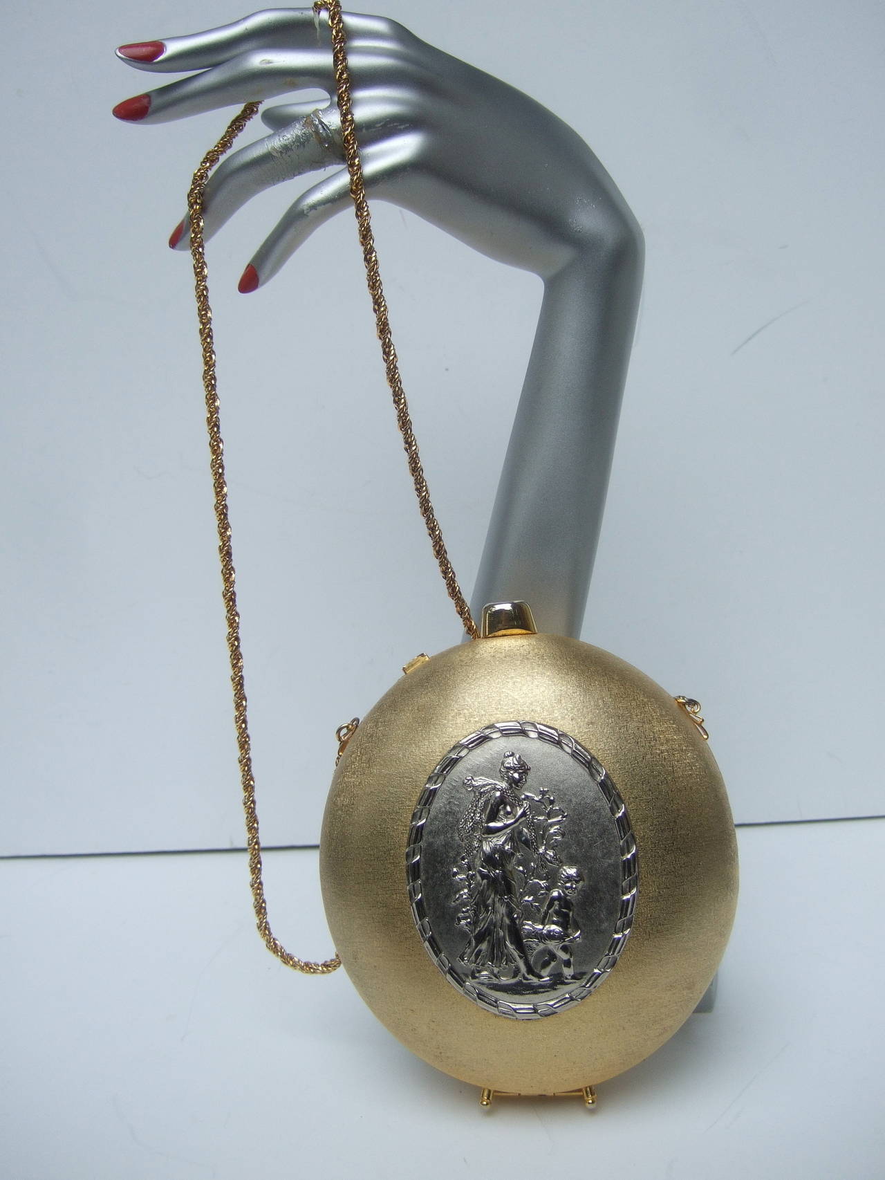 Opulent gilt metal evening bag designed by Rosenfeld c 1970
The lavish oval shaped evening bag is designed with satiny
luminous gilt metal. The center of the gilt metal purse is
decorated with a oval shaped silver metal plaque

The silver metal