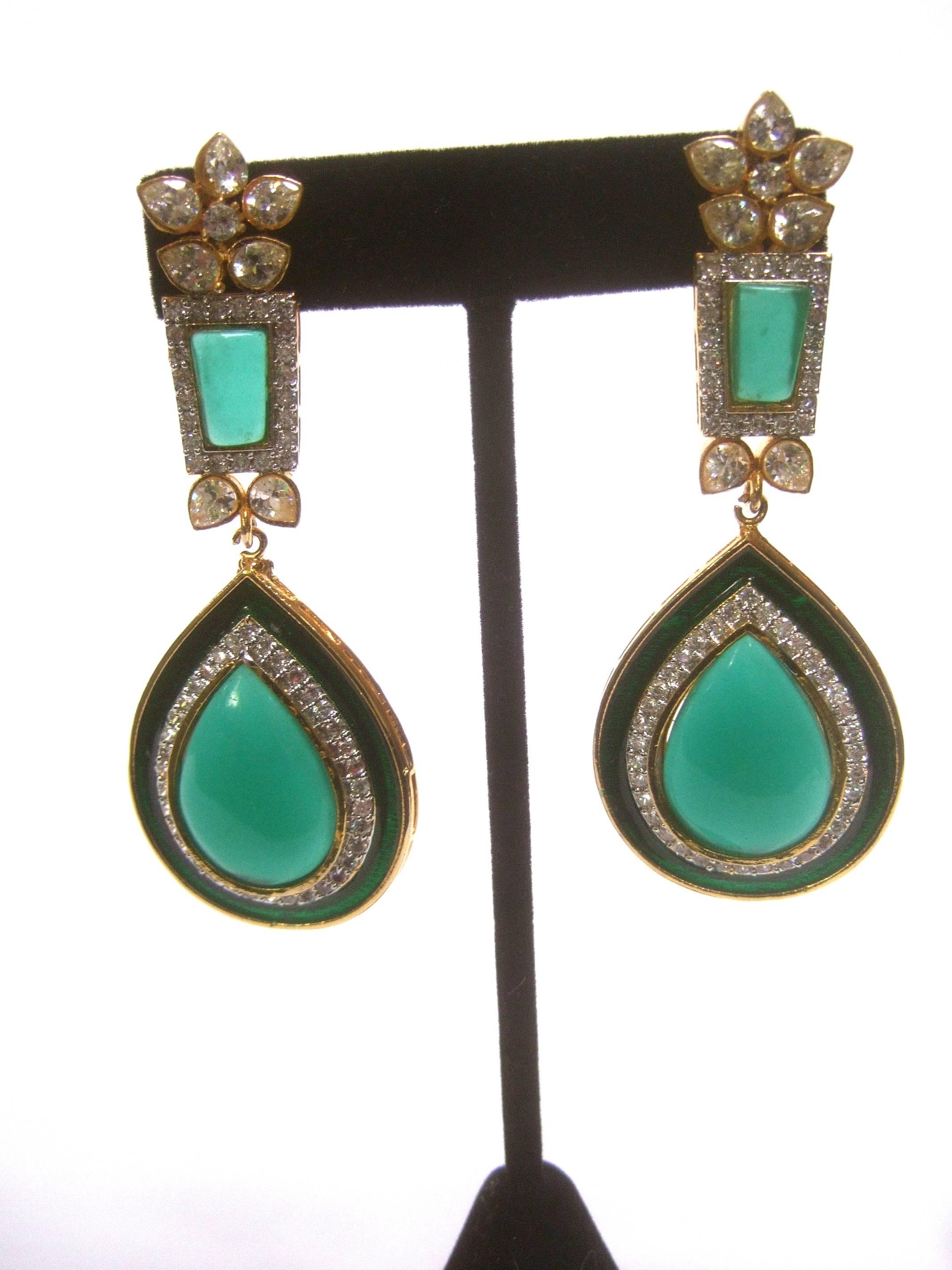 Exquisite emerald green poured glass massive tear drop earrings
The striking poured glass statement earrings are designed 
with a dangling green glass tear drop stone framed with 
glittering diamante crystals and green enamel 

The top of the