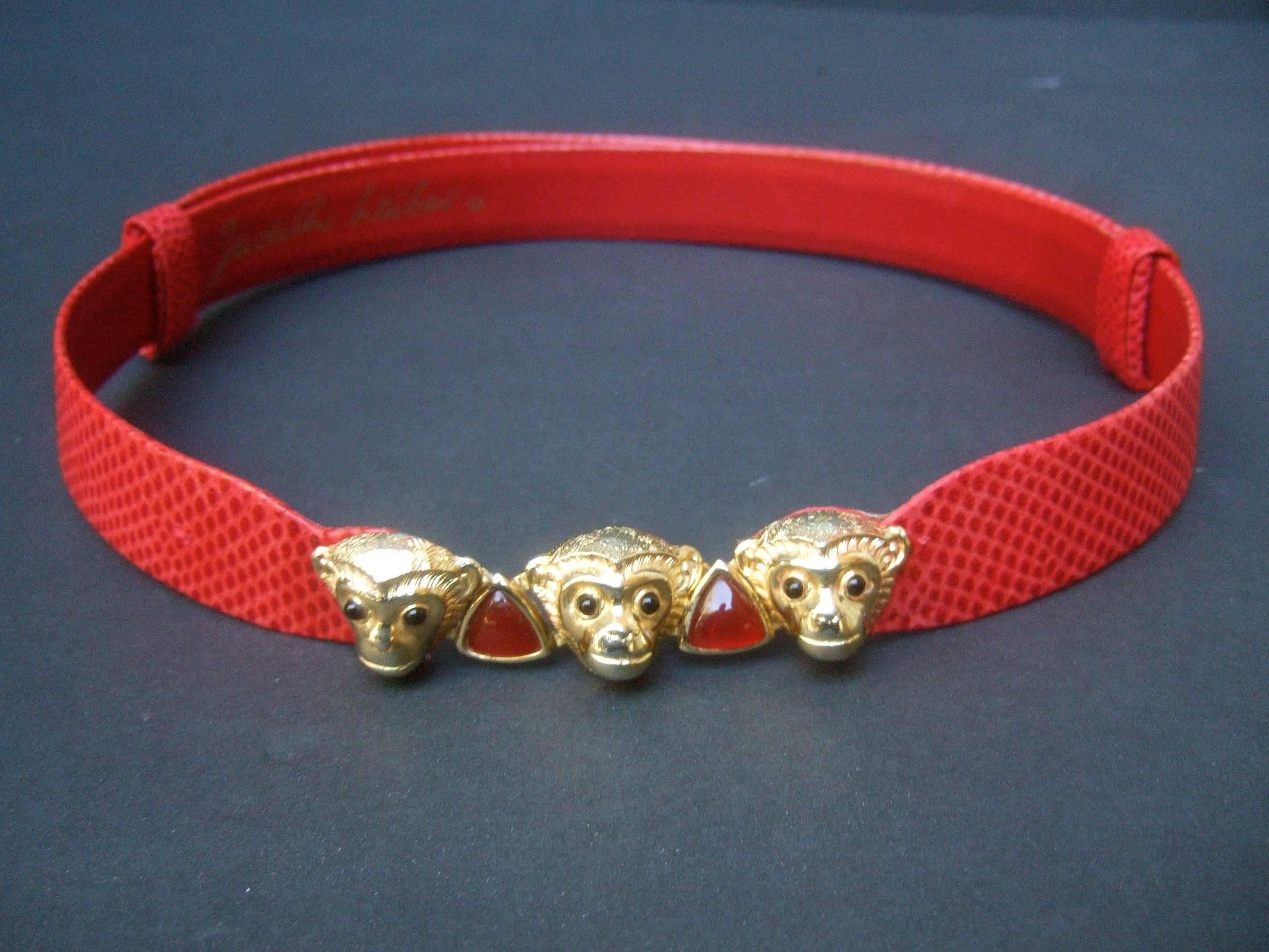 Judith Leiber Charming monkey buckle embossed red leather belt 
The stylish belt is designed with a trio of jeweled gilt metal monkeys
that serve as the buckle

The adorable monkeys are embellished with tiny black 
glass cabochon eyes. The center