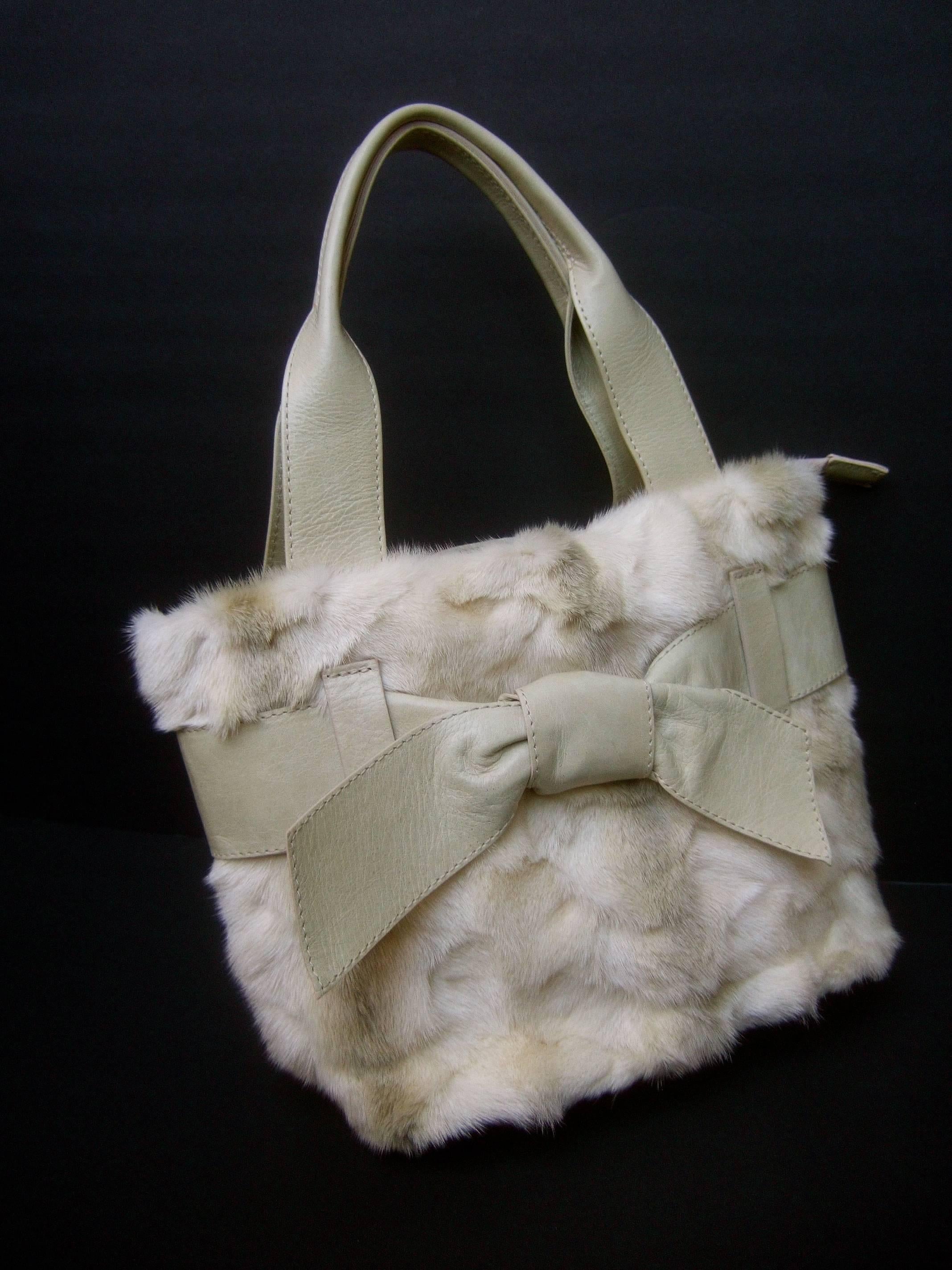 Italian Blonde mink fur ivory leather handbag 
The luxurious handbag is designed with plush 
sheared blonde mink fur on the front exterior
with subtle streaks of pale gray mink fur 

Accented with an ivory color leather bow that
runs across the