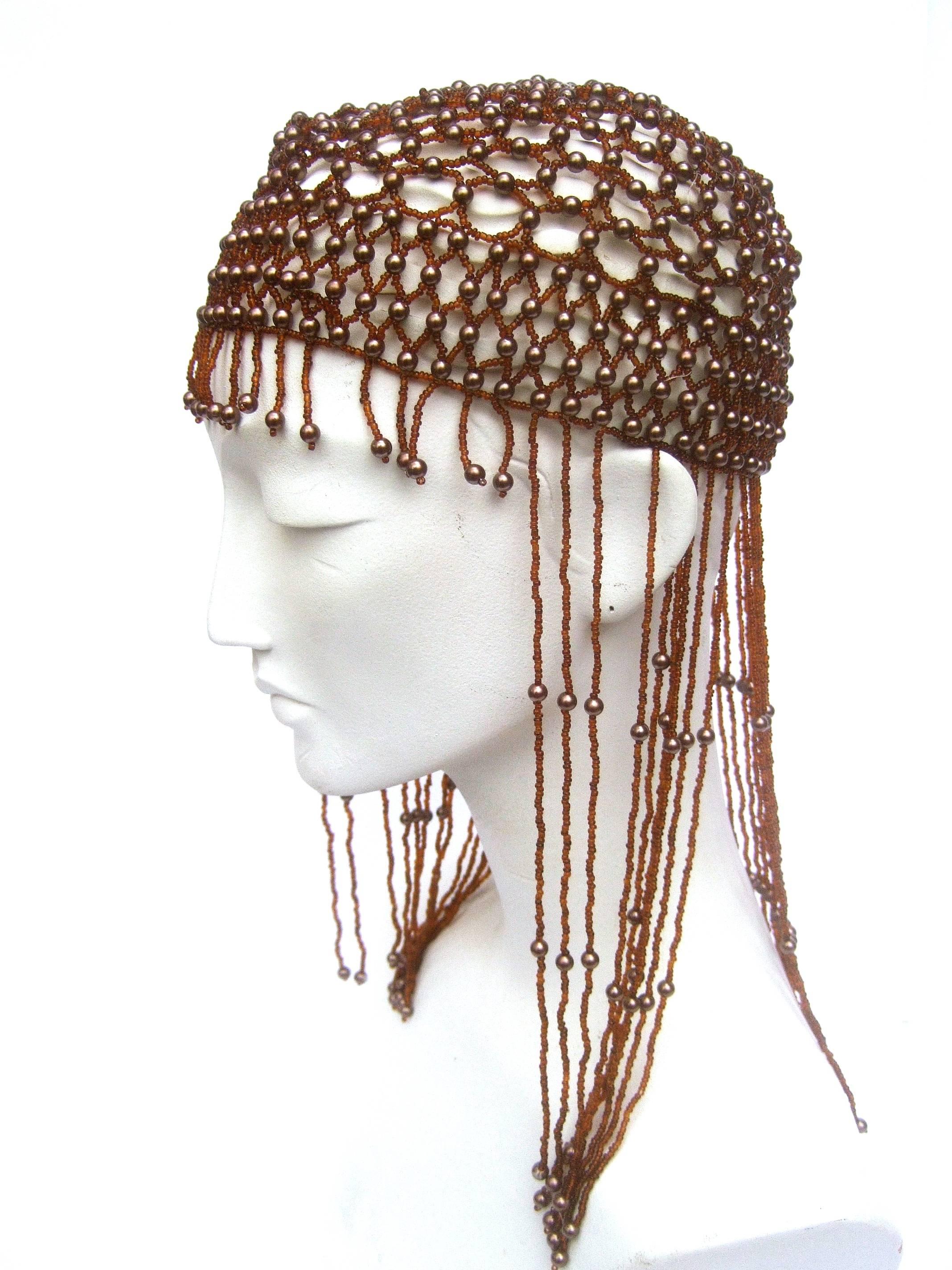 Exotic brown fringe beaded headpiece 
The unique headpiece is designed with a series
of beaded fringe tassels 

The beaded cap is accented with bronze enamel 
resin pearls. Running across the forehead are a 
series of beaded fringe tassels

Makes a