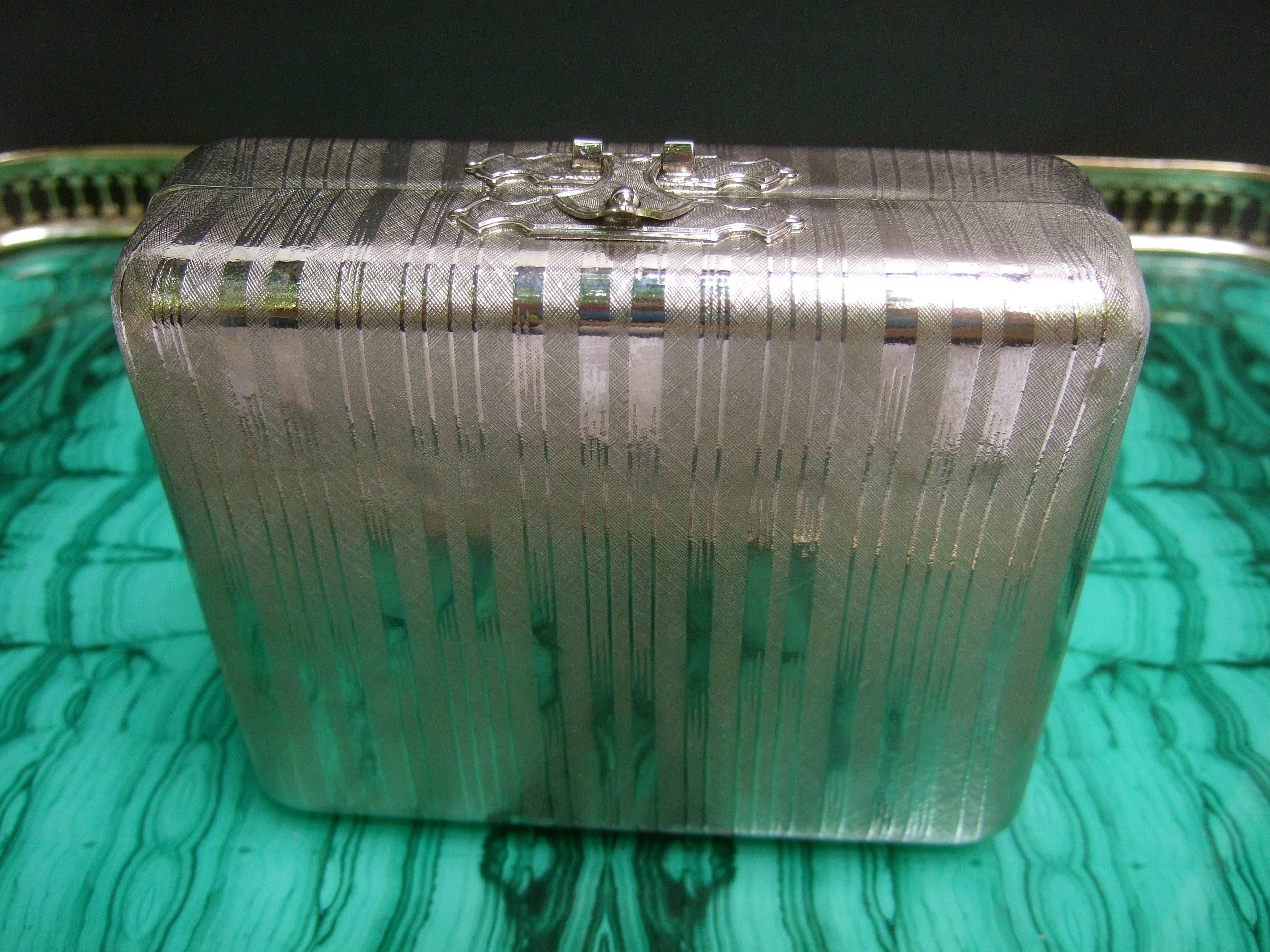 SAKS FIFTH AVENUE Italian silver metal minaudiere' evening bag c 1970s
The elegant evening bag is designed with silvertone metal accented 
with vertical etched lines throughout the exterior 

The versatile design may be carried as a chic clutch bag