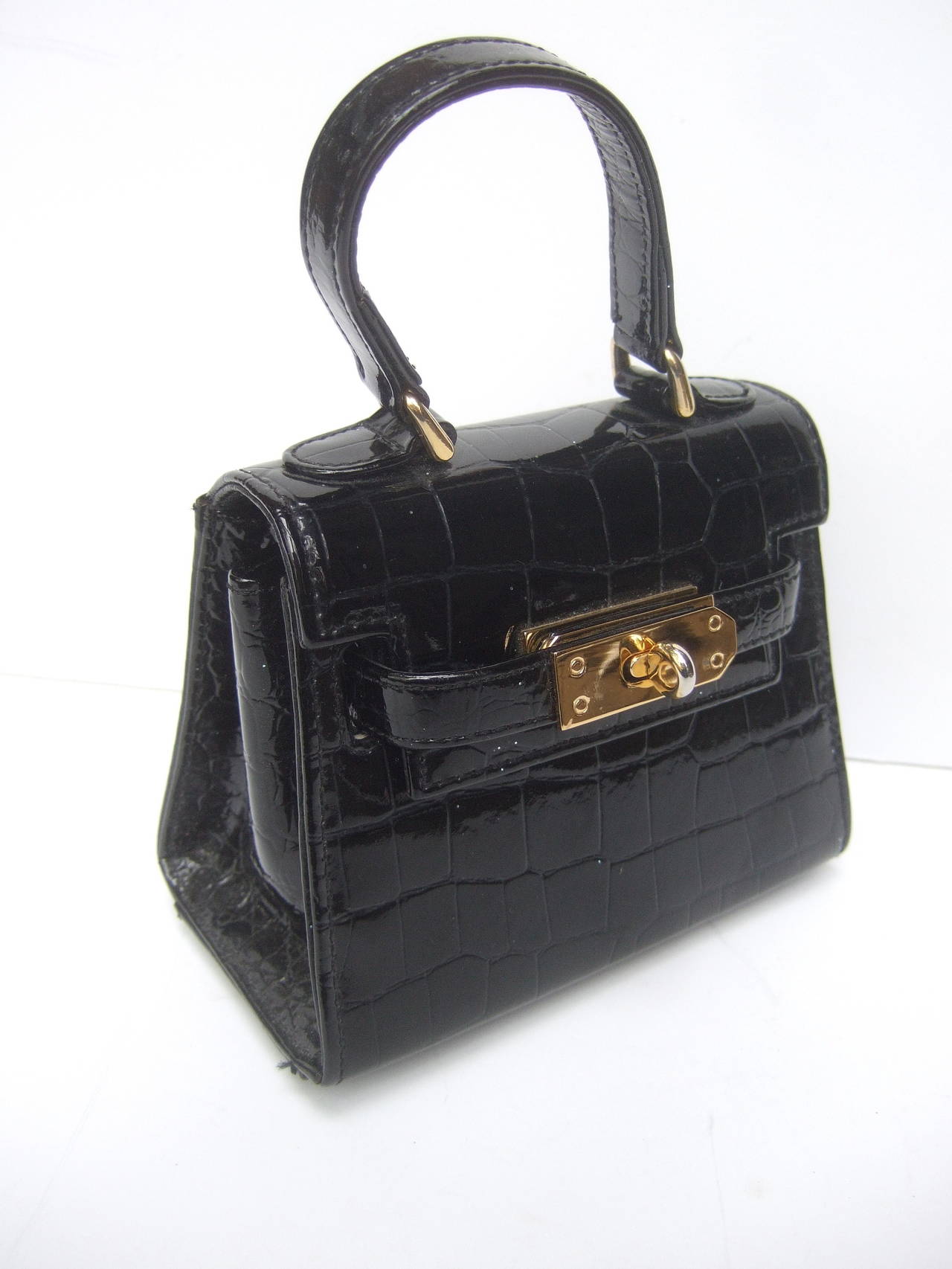 Diminutive black embossed leather handbag Made in Italy 
The sleek compact size patent leather handbag is covered
with glossy stamped leather that emulates reptile skin

The stylish diminutive handbag is embellished with gilt metal
hardware.