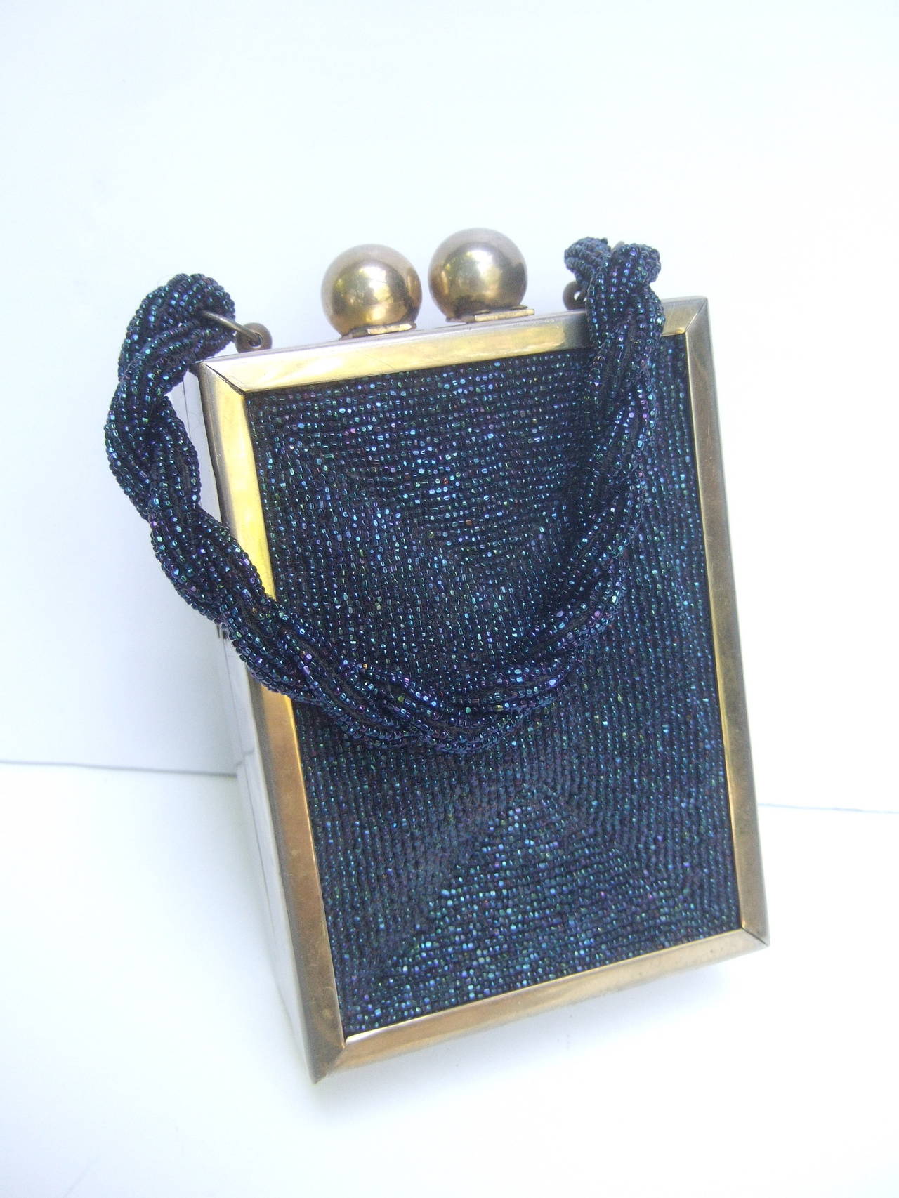 1940s Art Deco cobalt carnival glass beaded handbag
The sleek retro handbag is encrusted with glittering 
iridescent blue glass micro beads on both exterior
panels. The extravagant glass beaded panels are
designed in a subtle geometric raised