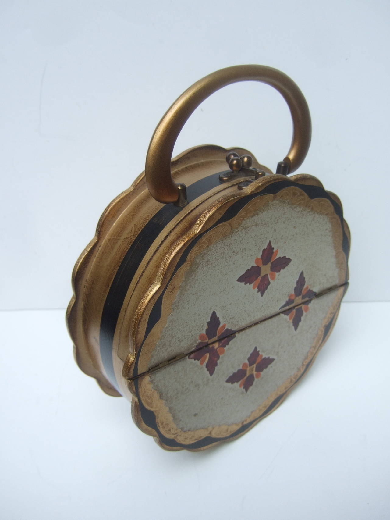 Unique Florentine style wood circular box style handbag c 1960s
The vintage round wood handbag is accented with gilt
enamel trim with burgundy & burnt orange painted
medallions on the front exterior panel

The wood border edges have a scalloped