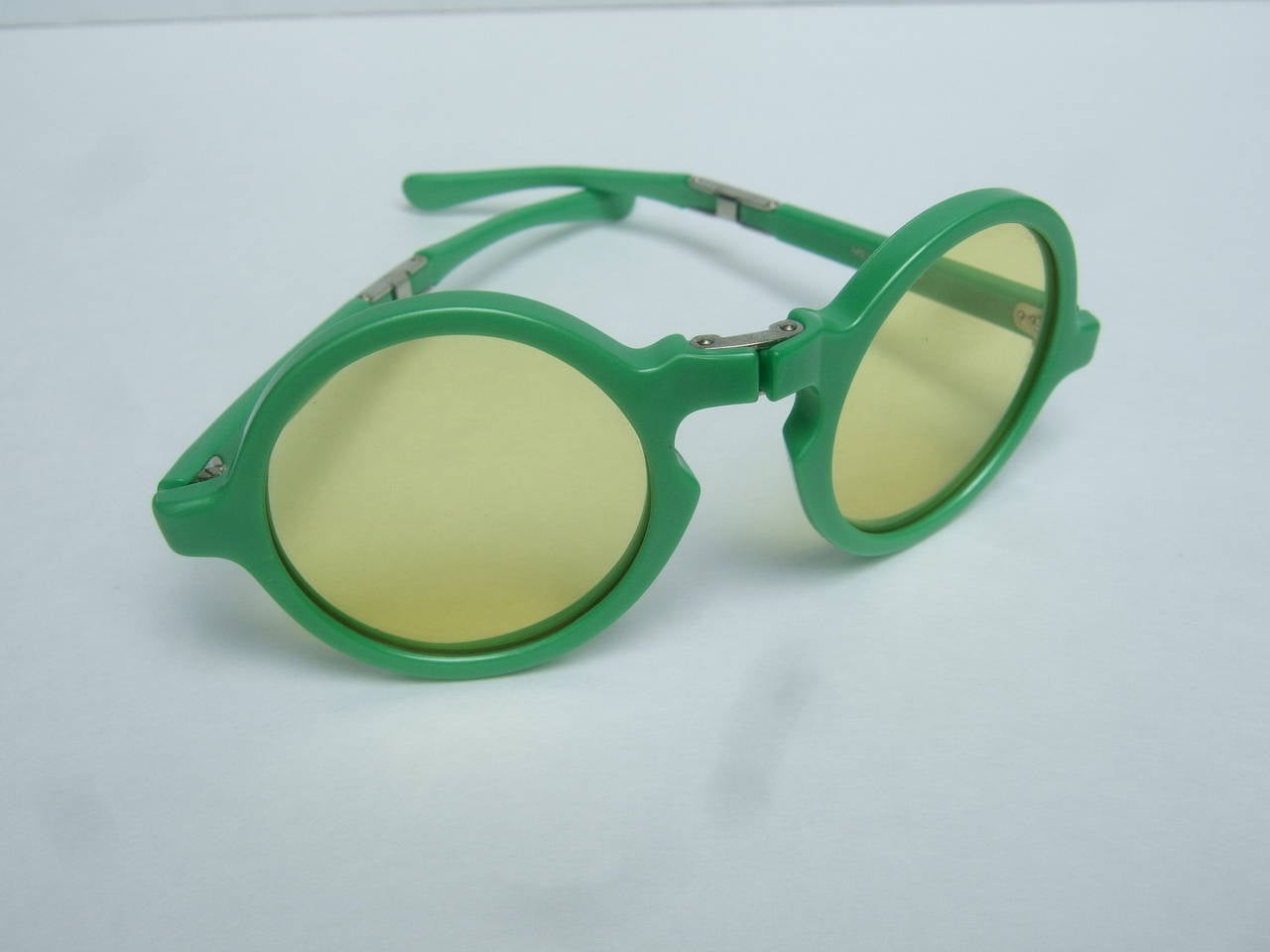 Avant-garde Italian green tinted sunglasses designed by Tuttifrutti Italy c 1960s

The mod retro sunglasses have a innovative unique design. The apple green 
lucite frames are designed with hinges. The frames fold to be stored in the
original