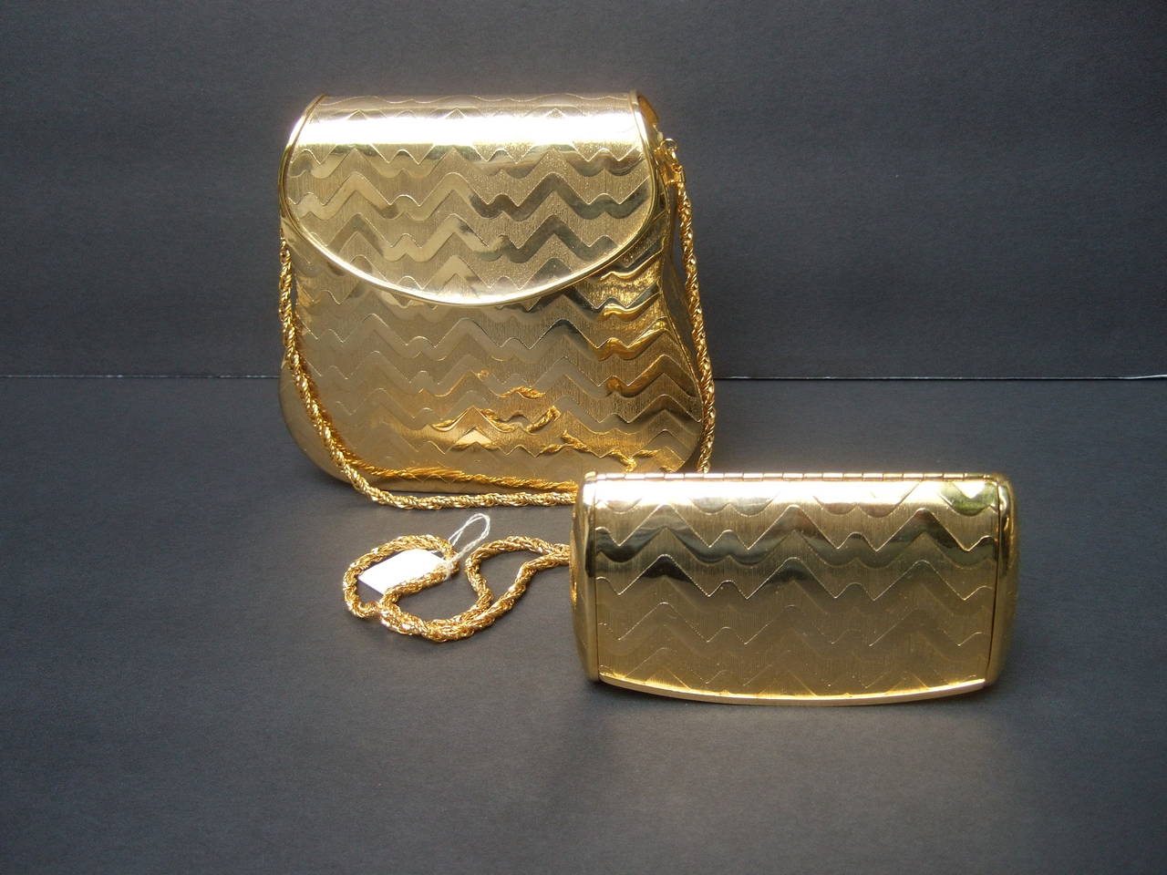 Elegant gilt metal evening bag set Made in Italy c 1970
The Italian evening bag is designed with luminous 
gilt metal in a chevron pattern that hangs from a
braided gilt metal stationary chain strap 

The metal exterior is designed with smooth