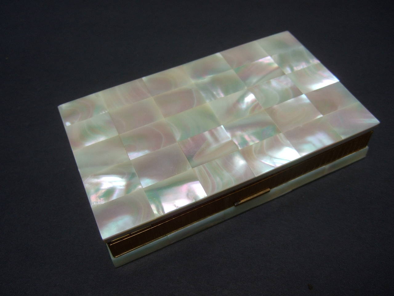 Opulent mother of pearl compact, cigarette case, clutch c 1960
The elegant case is embellished with geometric mother
of pearl inlaid veneered tiles on both exterior panels

The lavish mother of pearl case is framed with 
a gilt metal clasp. The