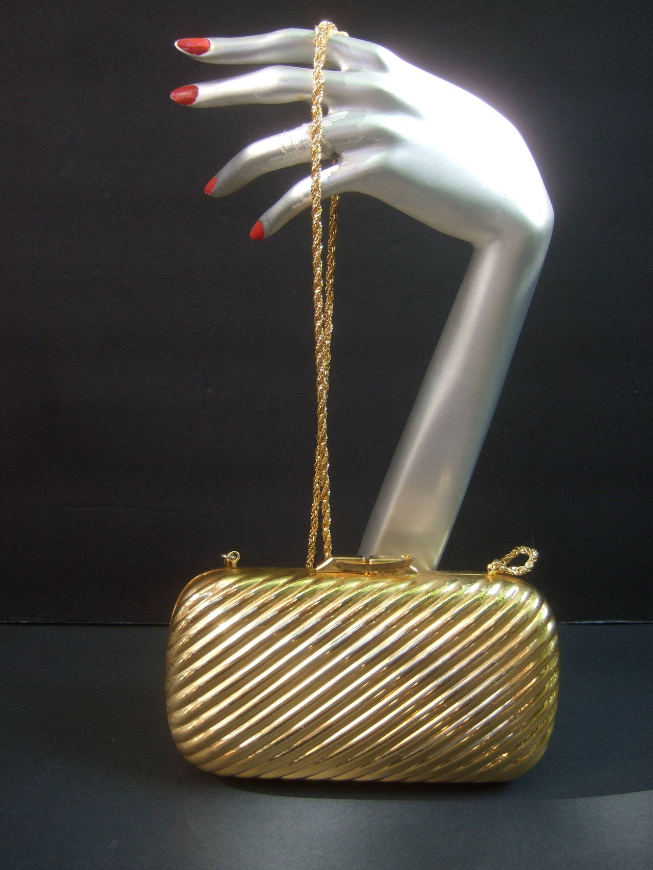 Italian gilt metal evening bag designed by Beoni Lucia c 1980
The elegant gold metal handbag is designed with grooved
metal bands on both exterior panels 

The verstatile evening bag transitions from a chic clutch 
bag converts to an elegant