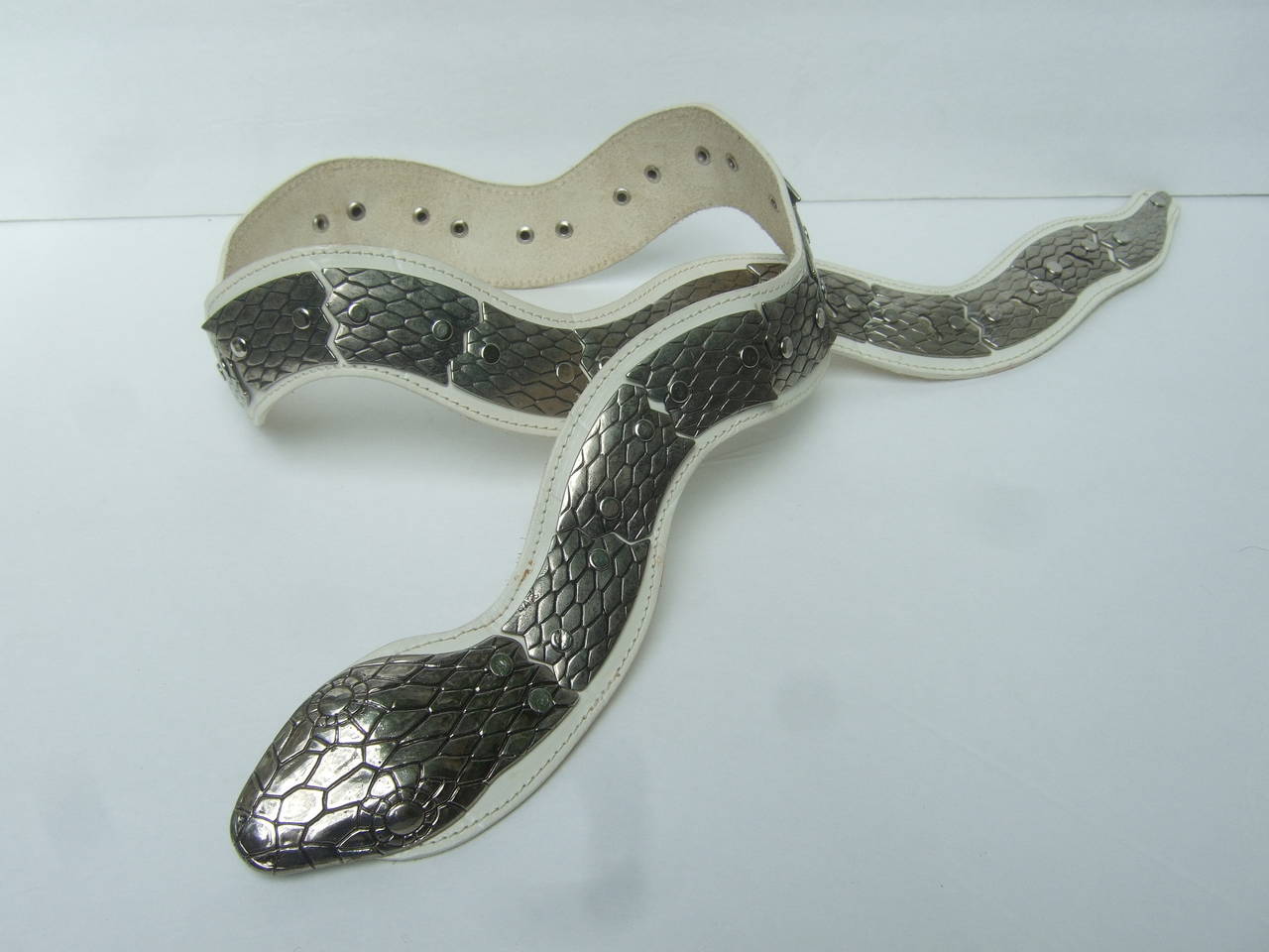 Exotic Italian silver metal articulated white leather snake belt c 1980s
The avant-garde belt is designed with heavy silver metal
links accented with impressed designs that emulate scales

The silver metal articulated links are designed in a