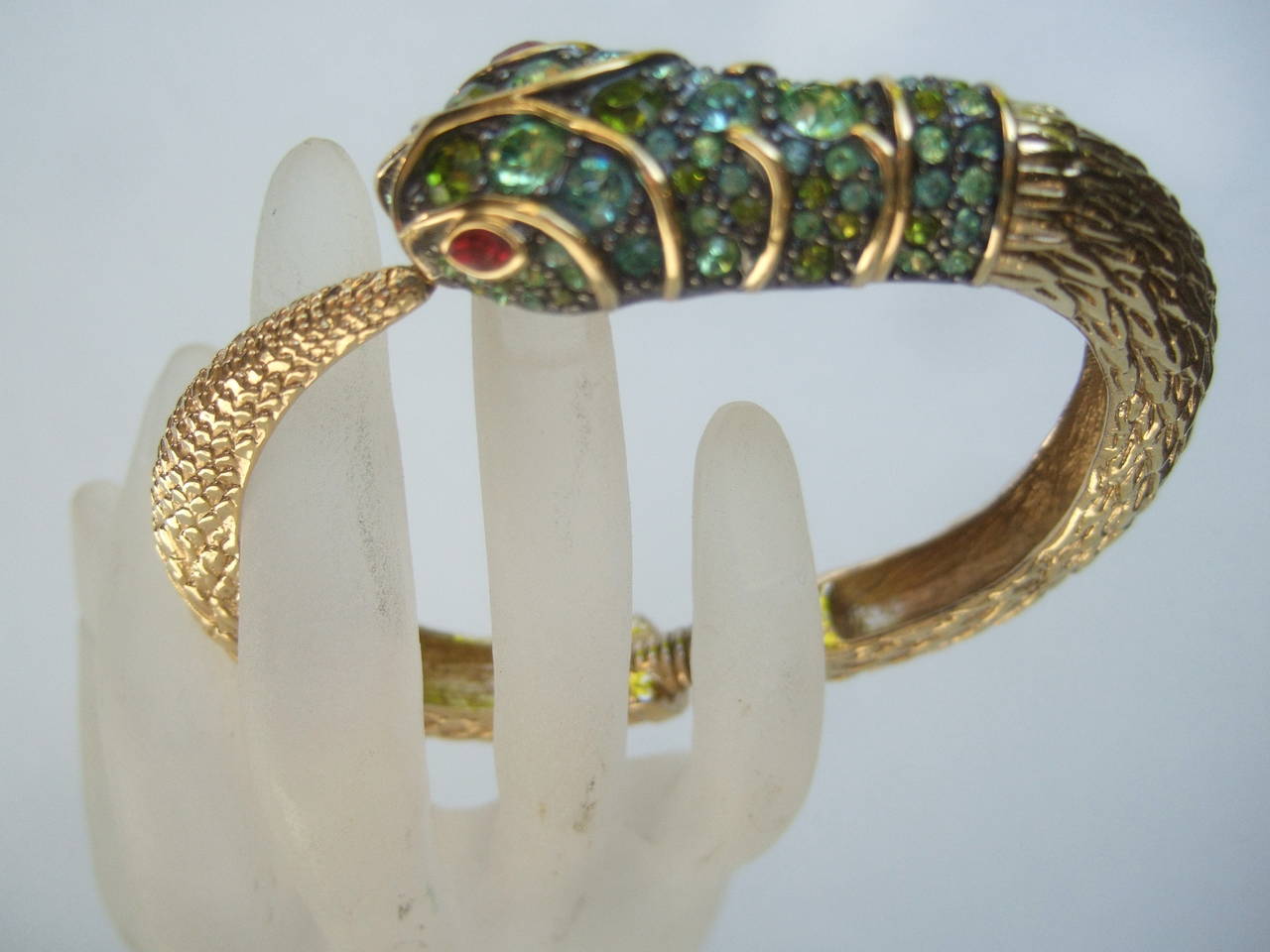 Ken Lane Exotic jeweled serpent bracelet c 1990 
The unique bracelet is designed with a coiled serpent
The serpent's head is encrusted with a collage of glittering
green crystals in various colors & sizes

The coiled serpent's body is designed