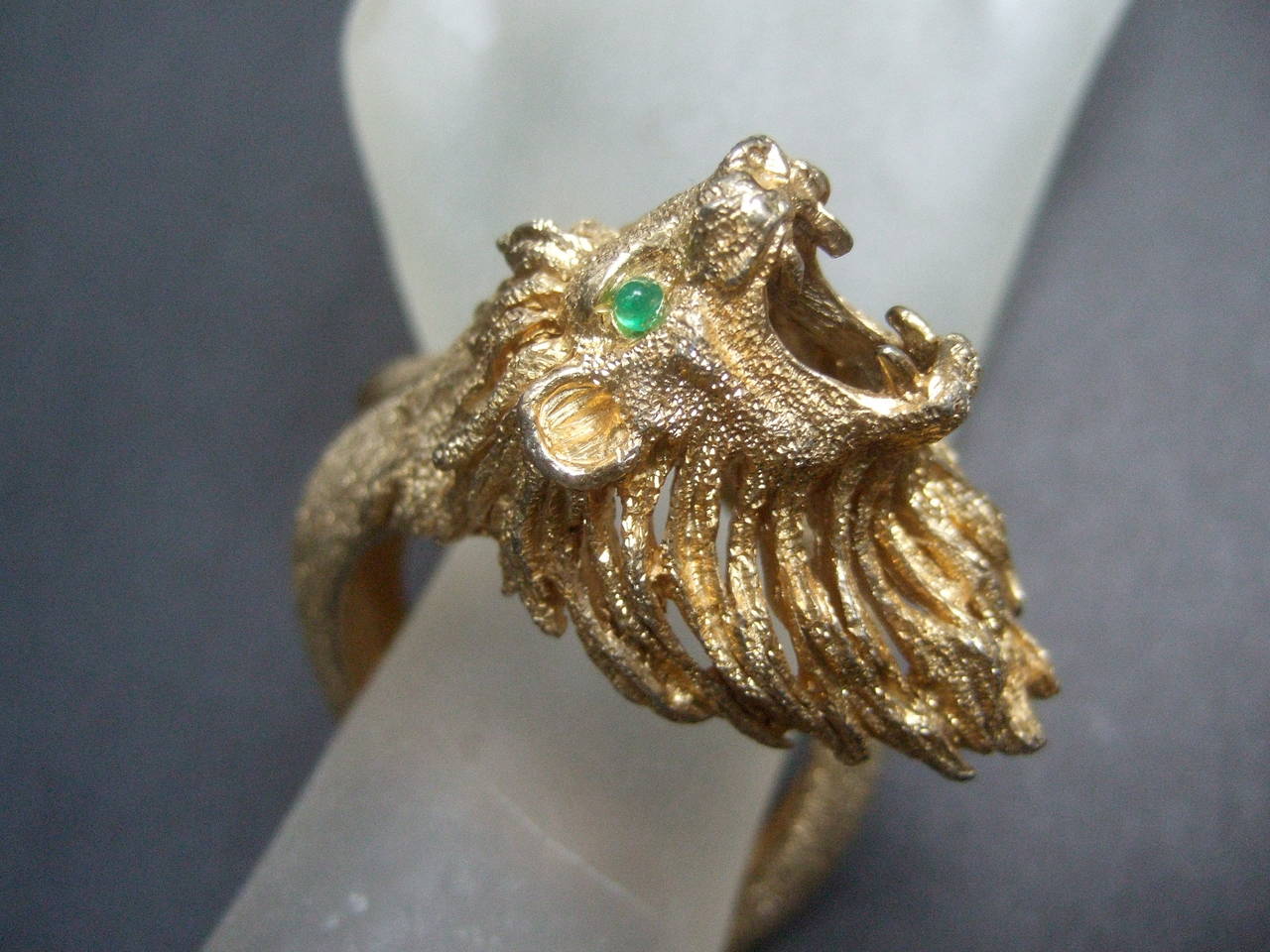 Ornate gilt metal lion bracelet designed by Les Bernard 
The figural costume bracelet is designed with an exotic 
gilt metal lions head embellished with green glass eyes 
The mane has sinuous wavy bands that emulate fur 

The lions expression