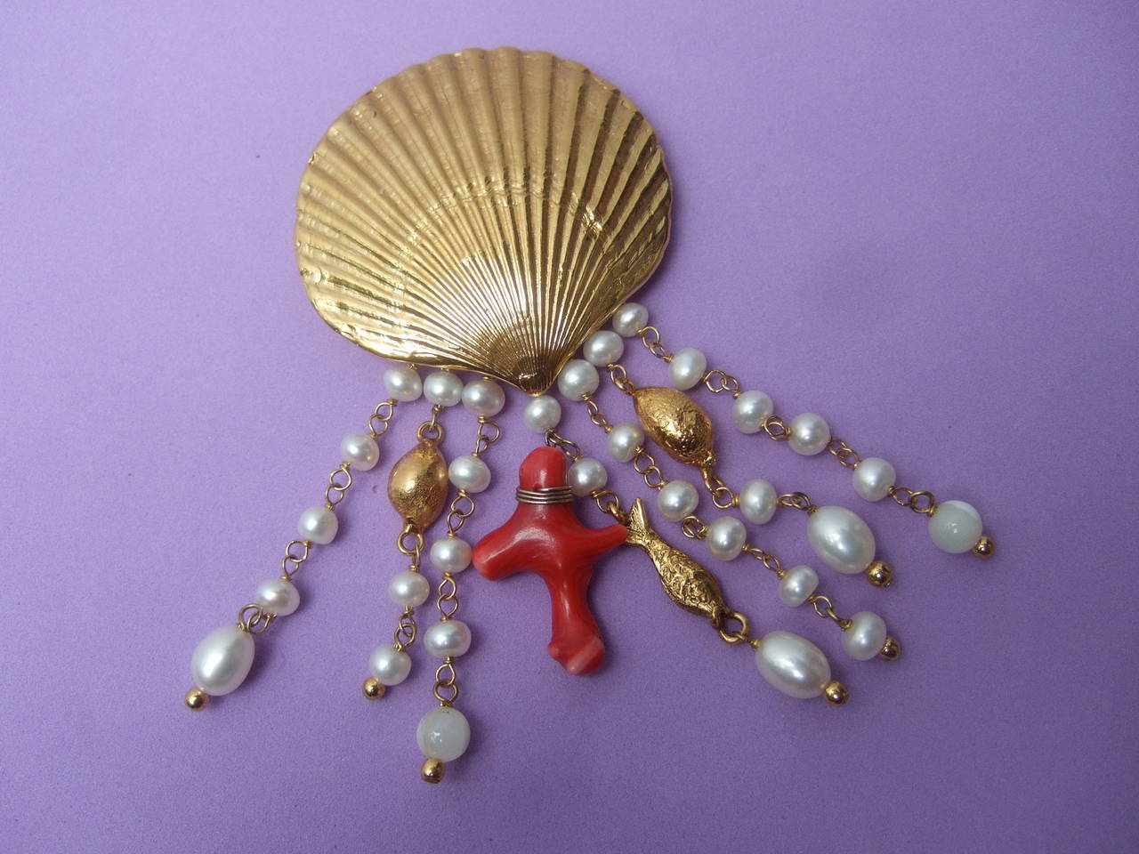 Goossen's Paris Gilt scallop shell sea life brooch c 1990
The elegant designer brooch is adorned with a gilt
metal scallop with rows of dangling embellishments 

The brooch is designed with rows of resin enamel
pearls interspersed with two gilt