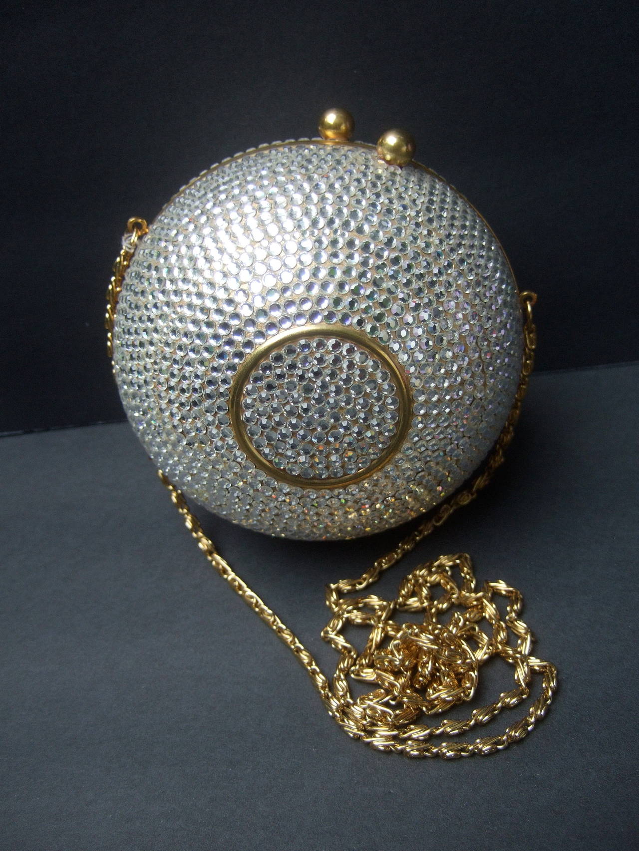 Opulent crystal encrusted orb shaped evening bag c 1980
The elegant sphere shaped evening bag is embellished 
with glittering diamante crystals throughout the exterior

The exterior center on both sides is accented with 
a gilt metal circle