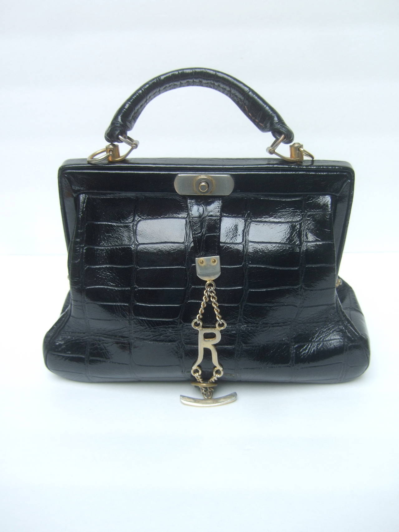 Roberta Di Camerino Sleek embossed black leather handbag Made in Italy 
The chic Italian handbag is designed with high gloss embossed leather
that emulates reptile scales

The elegant retro handbag is embellished with gilt metal chains
with Di