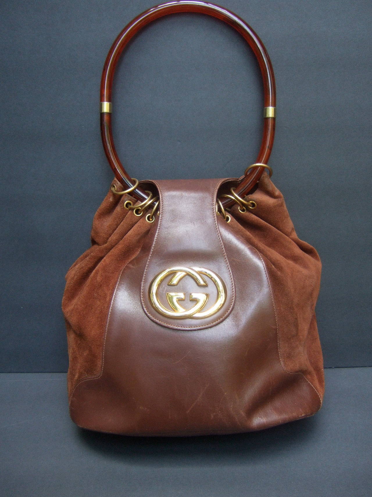 Gucci Italy Rare Brown leather & suede handbag c 1970
The stylish Italian handbag is carried with a sleek amber
tortoise shell lucite oval shaped handle 

The front exterior is adorned with Gucci's large
gilt metal interlocked initials. The