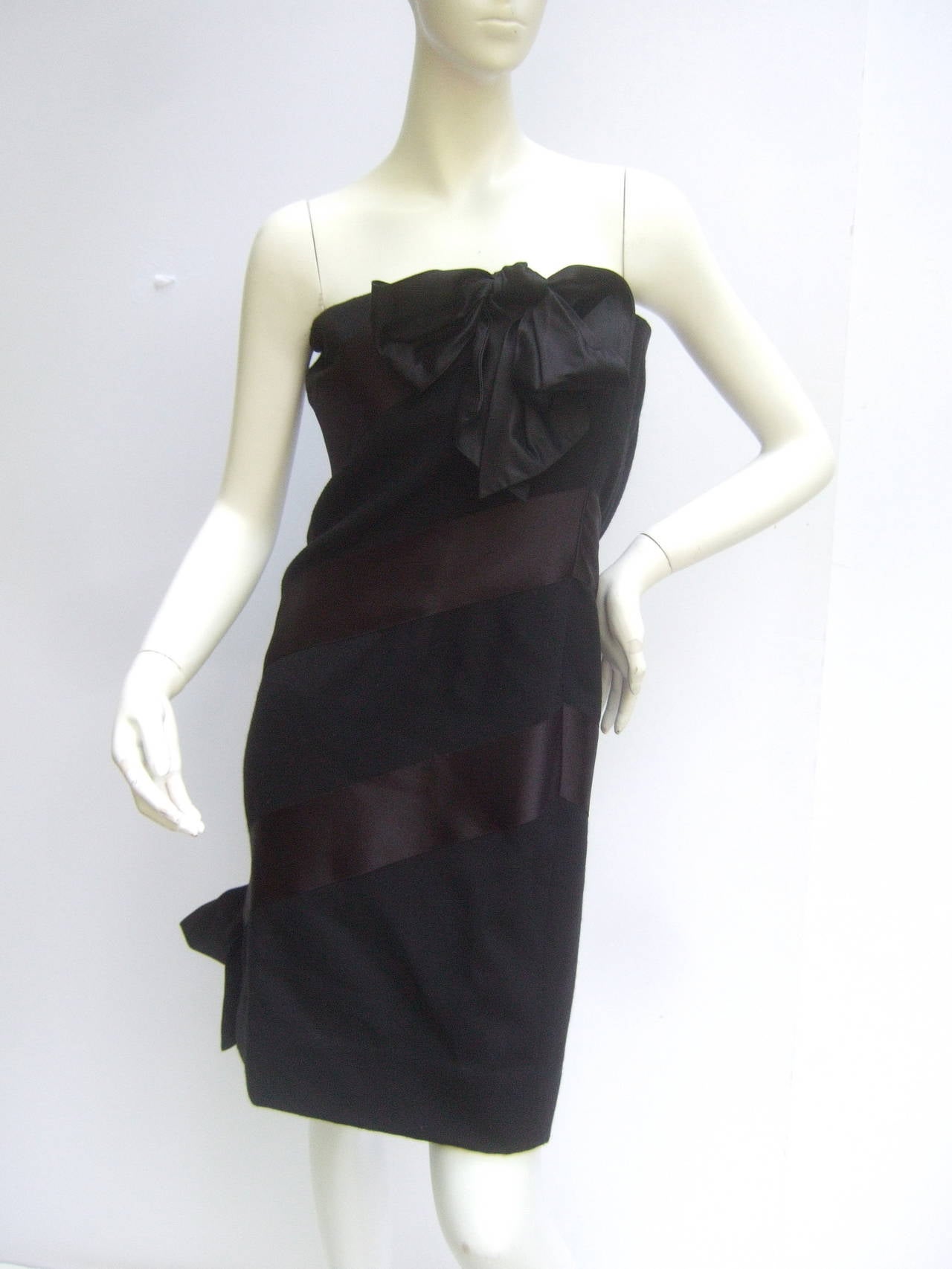 Bill Black Chic black wool & satin strapless cocktail dress
The classic evening dress is designed with wool & satin
stripes. The wide satin stripe panels are on a diagonal slant

The bodice is accented with a billowy black satin bow
The bow