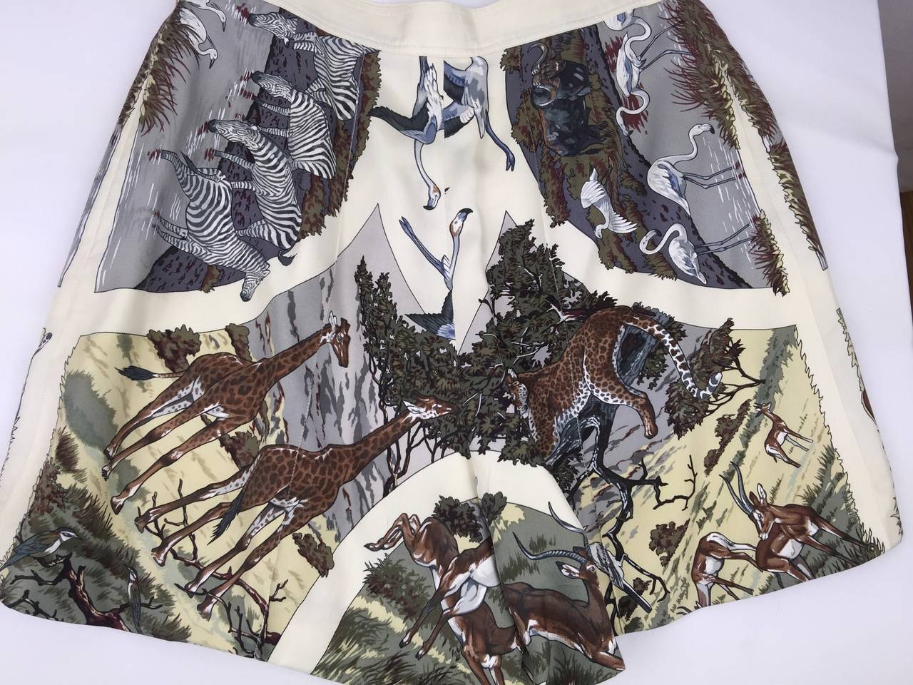 Rare and special vintage jungle themed safari style silk shorts by Hermes.  
Amazingly rich detail of exotic flora and fauna in classic understated tones on ivory background. 
Slightly flared with two slit pockets.  Pearl buttons engraved Hermes