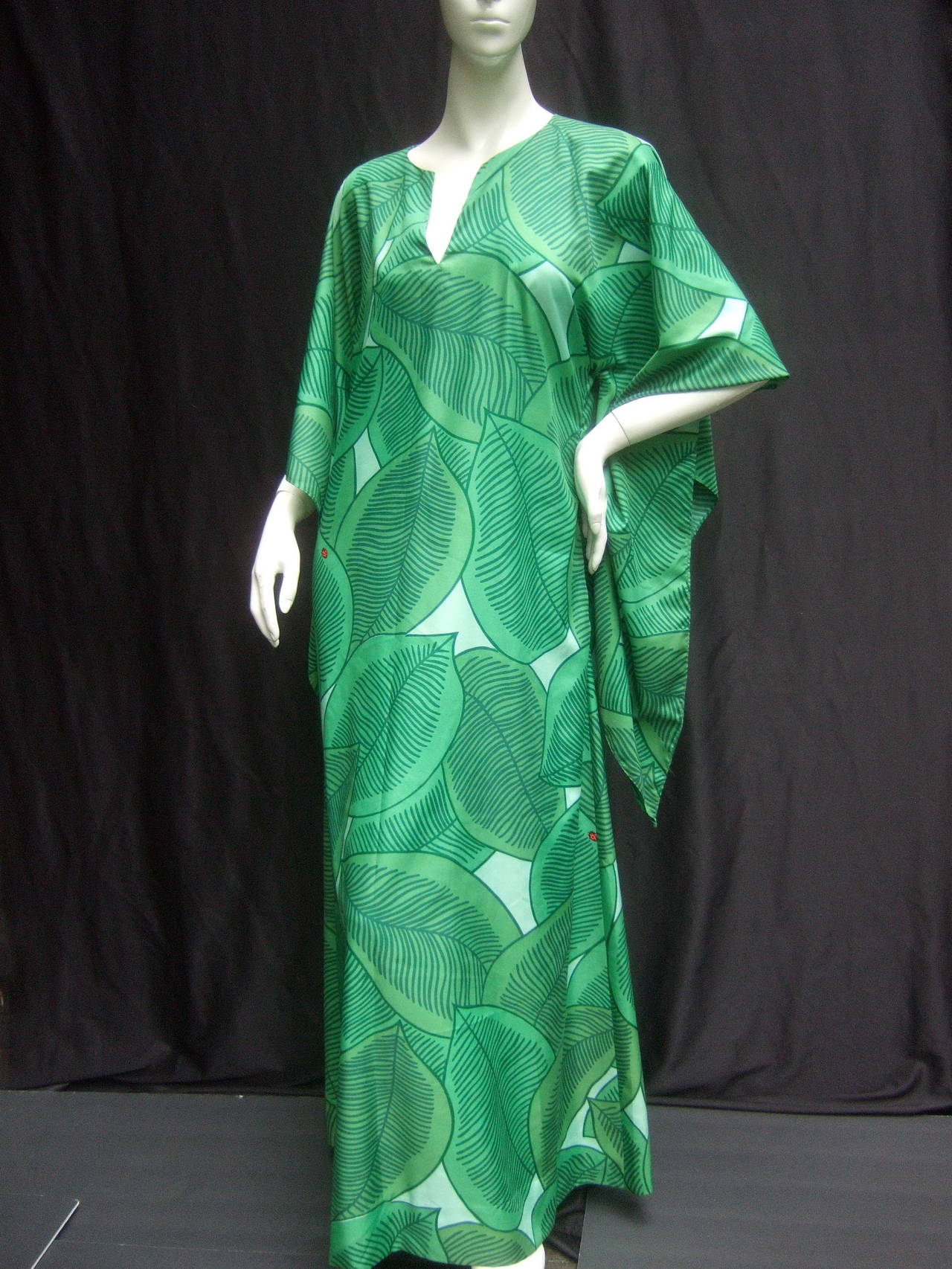 Lush green tropical print caftan gown c 1970
The unique gown is illustrated with vibrant 
green foliage accented with a few tiny 
restrained lady bugs 

The chic caftan is designed with dramatic 
butterfly wing sleeves. The neckline has
a
