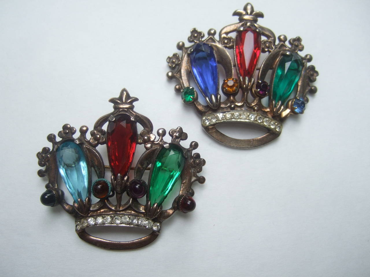 Sterling crystal pair of crown brooches c 1950
The elegant mid century brooches are embellished
with jewel tone crystals with diamante crystal accents 

The pair of sterling coronation crown brooches 
have a rose vermeil finish. The figural