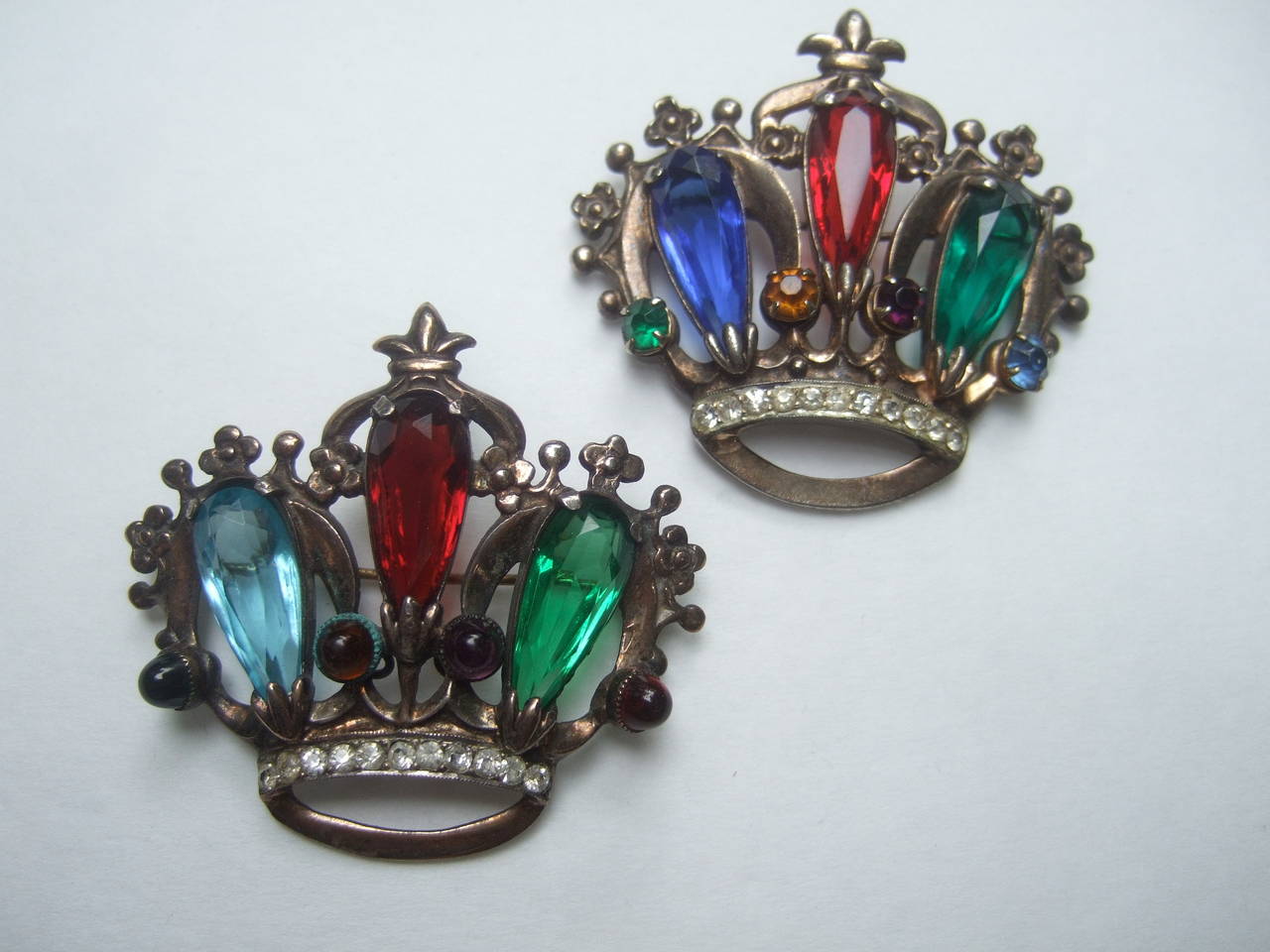 Paire de broches couronnes en cristal d'argent, C.I.C., 1950
Les élégantes broches du milieu du siècle sont embellies
avec des cristaux de couleur Jewell et des accents de cristal diamantés 

Paire de broches en argent représentant la couronne