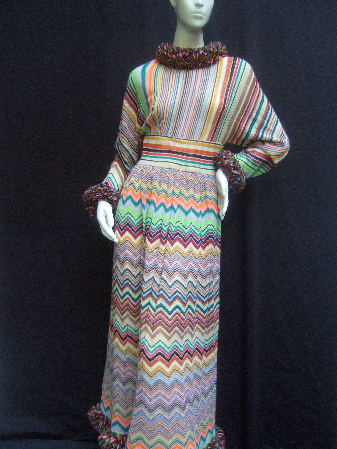 1970s Striped knit chevron maxi gown 
The chic retro knit gown is designed with
vertical, horizontal and zig-zag chevron 
stripes in a collage of earth tone and pastel 
colors 

The collar, cuffs and hemline are accented
with frayed fringe
