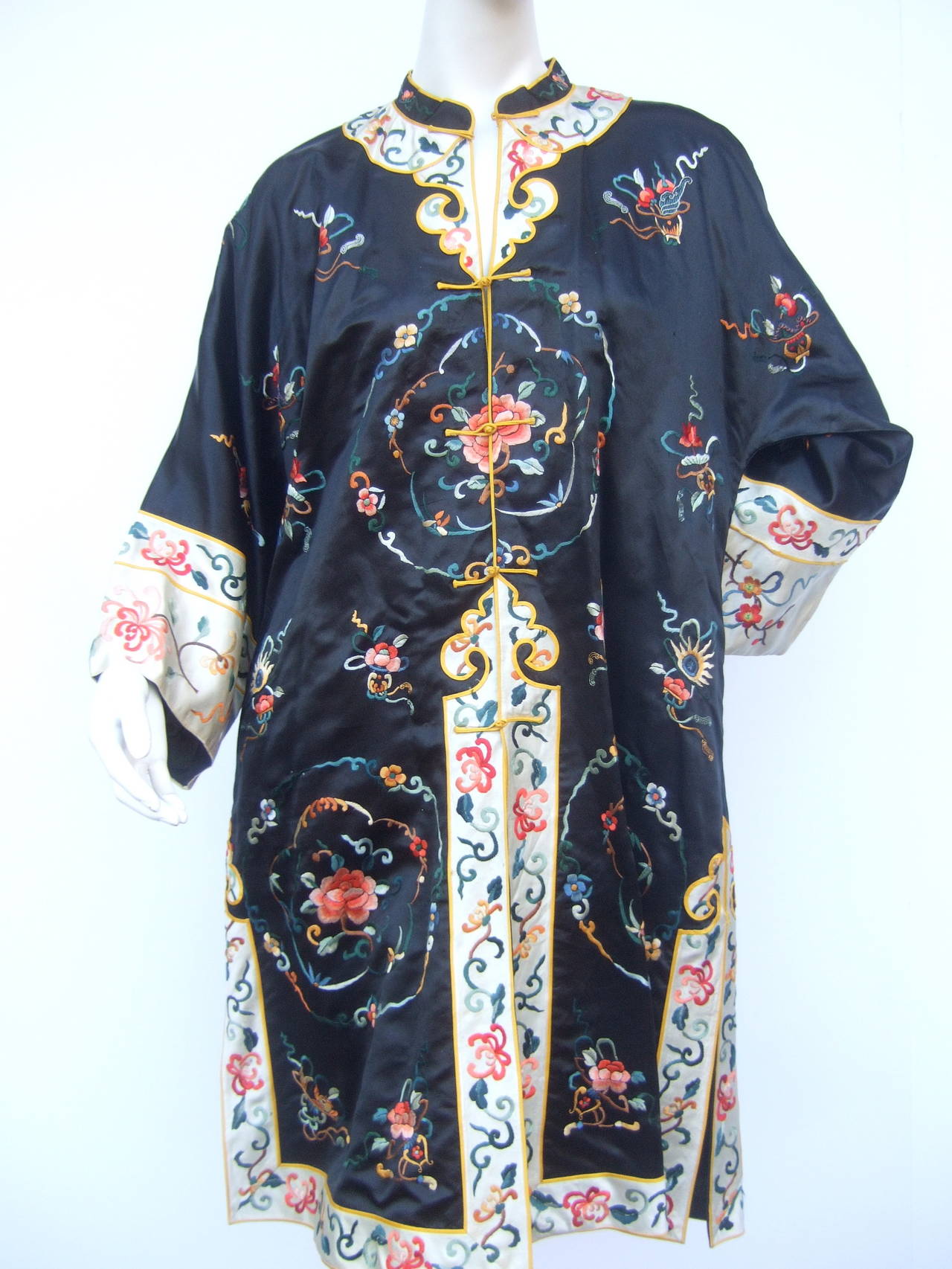 Exotic Chinoiserie embroidered satin duster coat  1980s
The luxurious black satin duster coat is embellished 
with elaborate floral embroidery throughout

The collar, cuffs, lower front opening, hemline and
sides are designed with contrasting