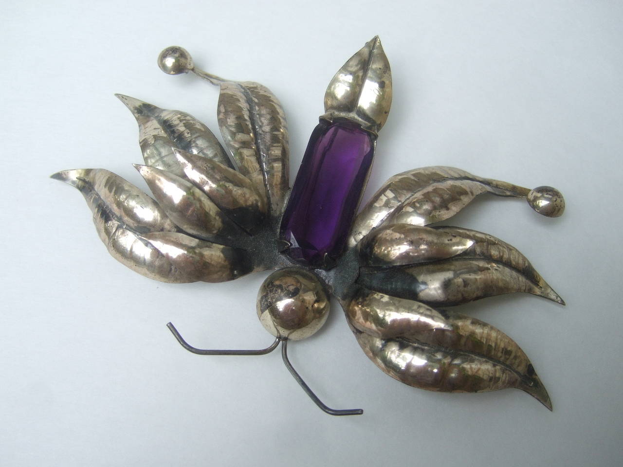 Massive sterling crystal butterfly brooch c 1950s
The huge sterling artisan brooch is designed with
an exotic butterfly. The large scale butterfly is 
designed with a rectangular amethyst crystal 

The elaborate sterling wings are